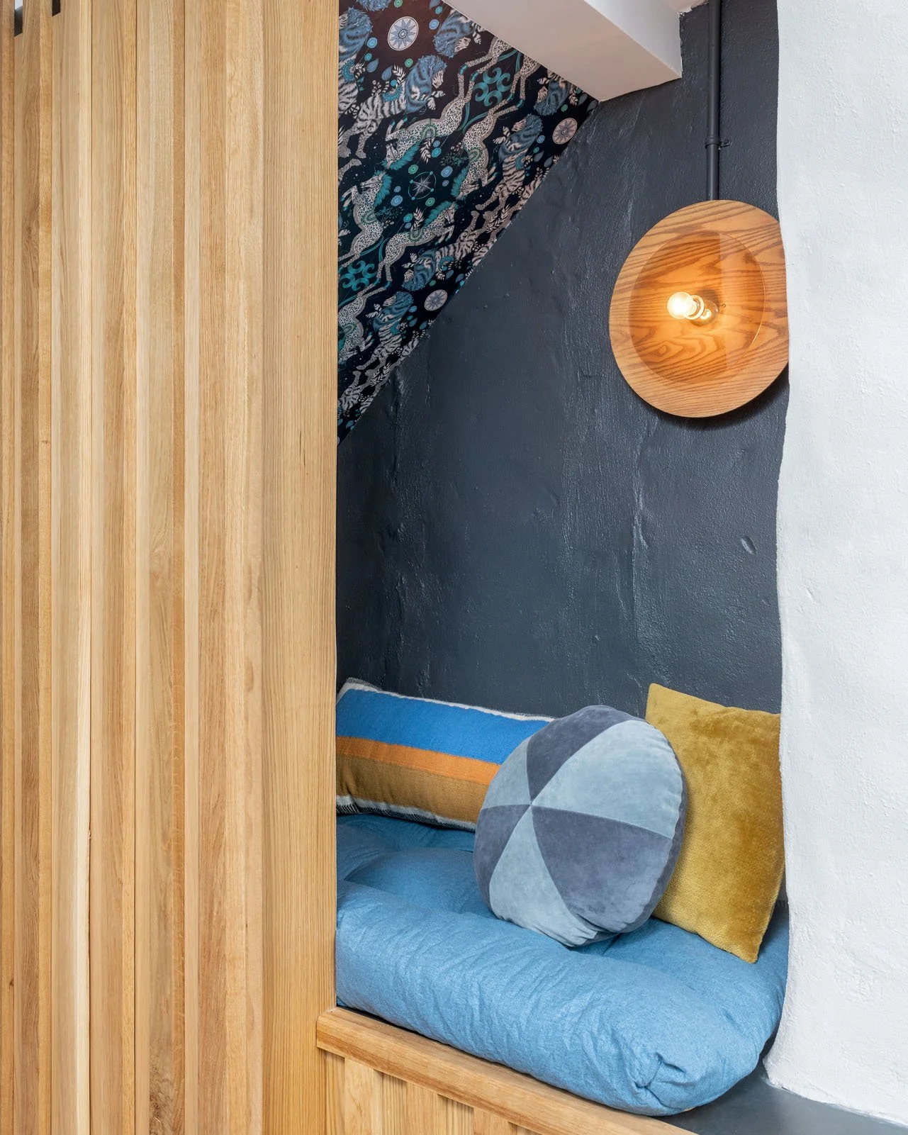 Textured gray wall behind reading nook with colorful pillows