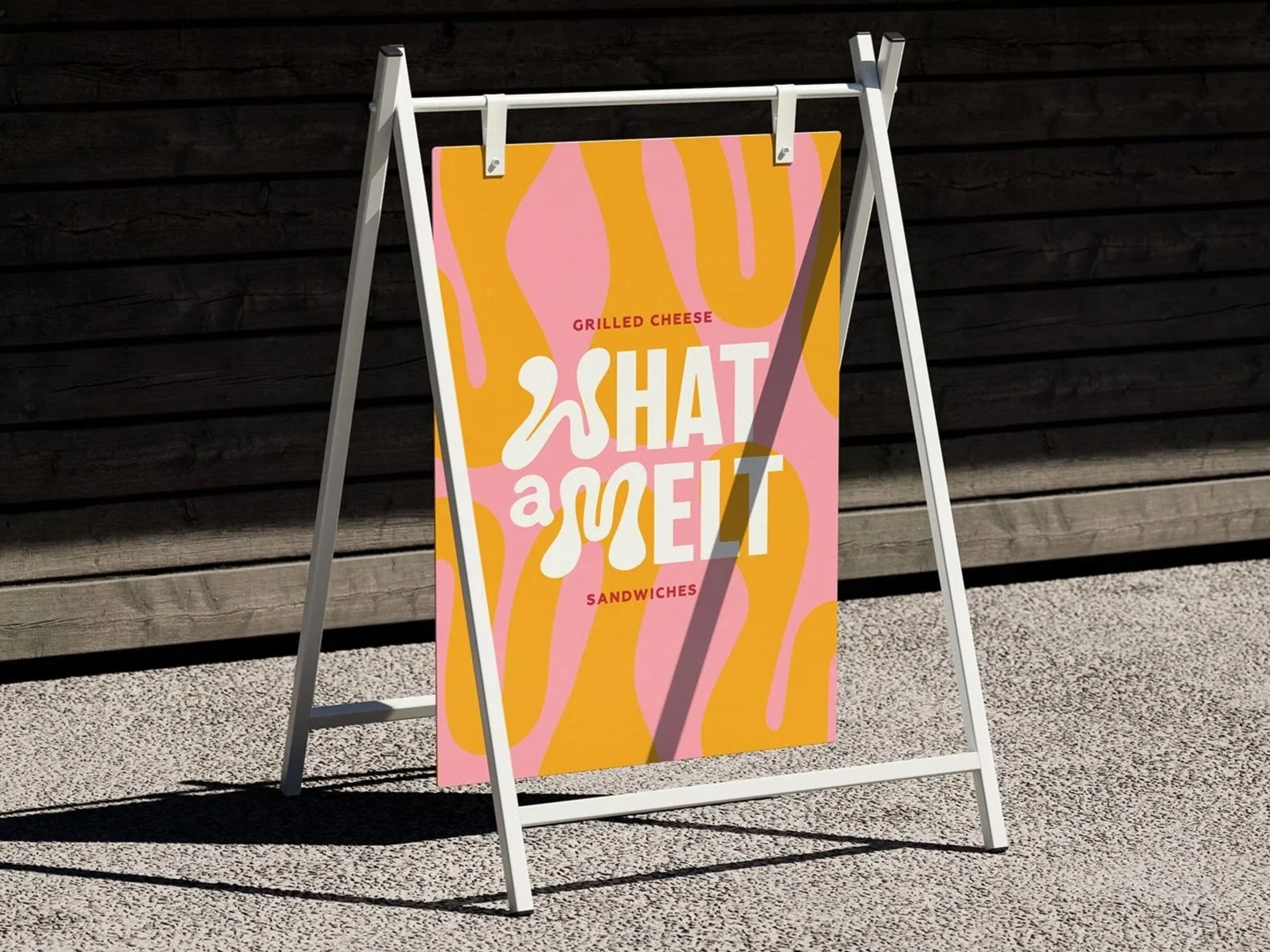 A sidewalk sign advertising grilled cheese sandwiches with the text "SHAT a MELT" against a colorful yellow and pink background, with the words "grilled cheese" and "sandwiches" in smaller red text.