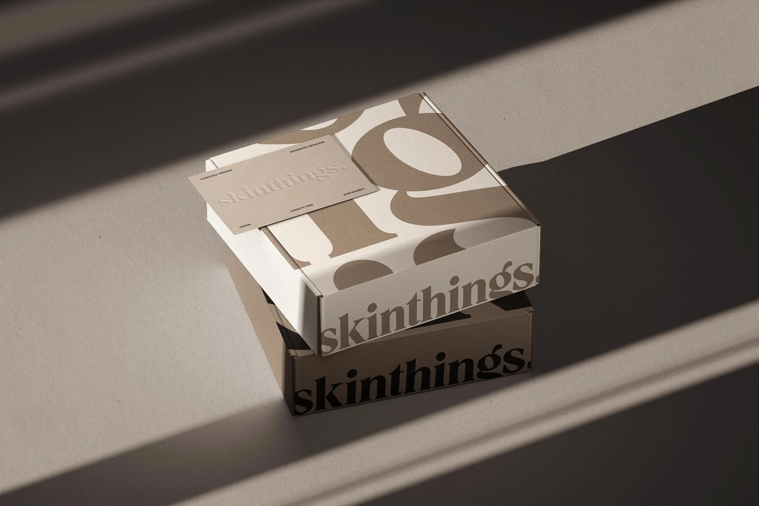 Two boxes with the word 'skinhings' on them, placed on a beige surface with strong sunlight and shadows.