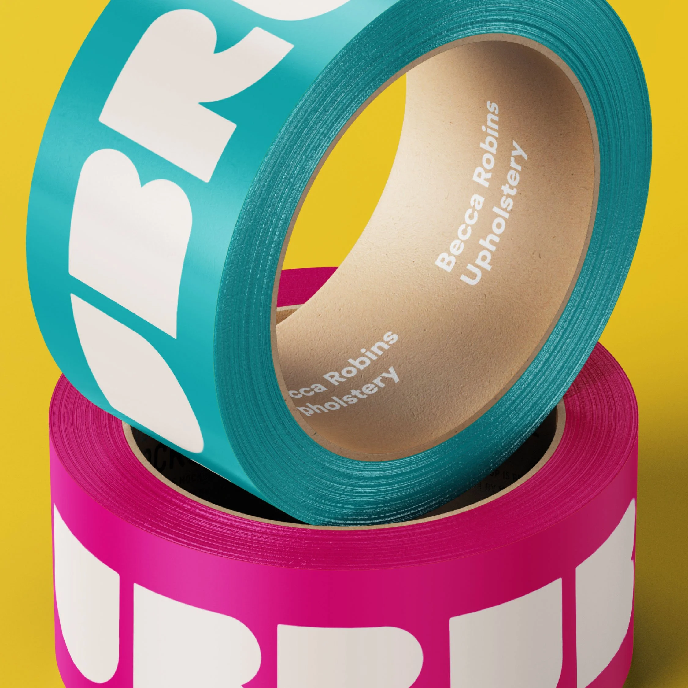 Two rolls of colored tape, one teal and one pink, stacked on top of each other against a yellow background. The inner side of each roll displays the text 'Becca Robins Upholstery'.