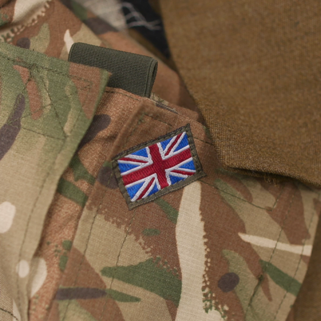 Close-up of a camouflage military uniform with a Union Jack flag patch attached.