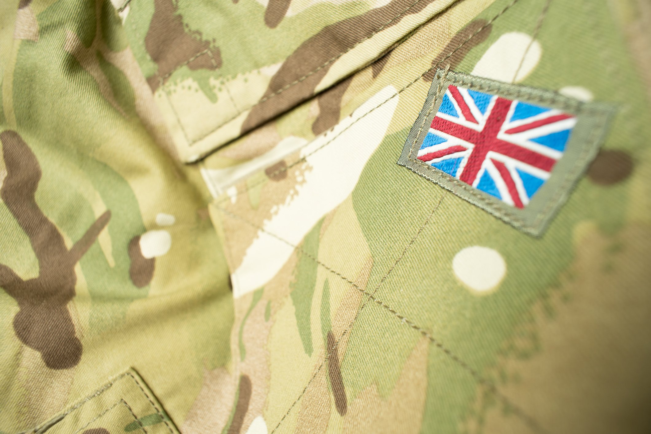 Close-up of camouflage military fabric with a Union Jack patch.