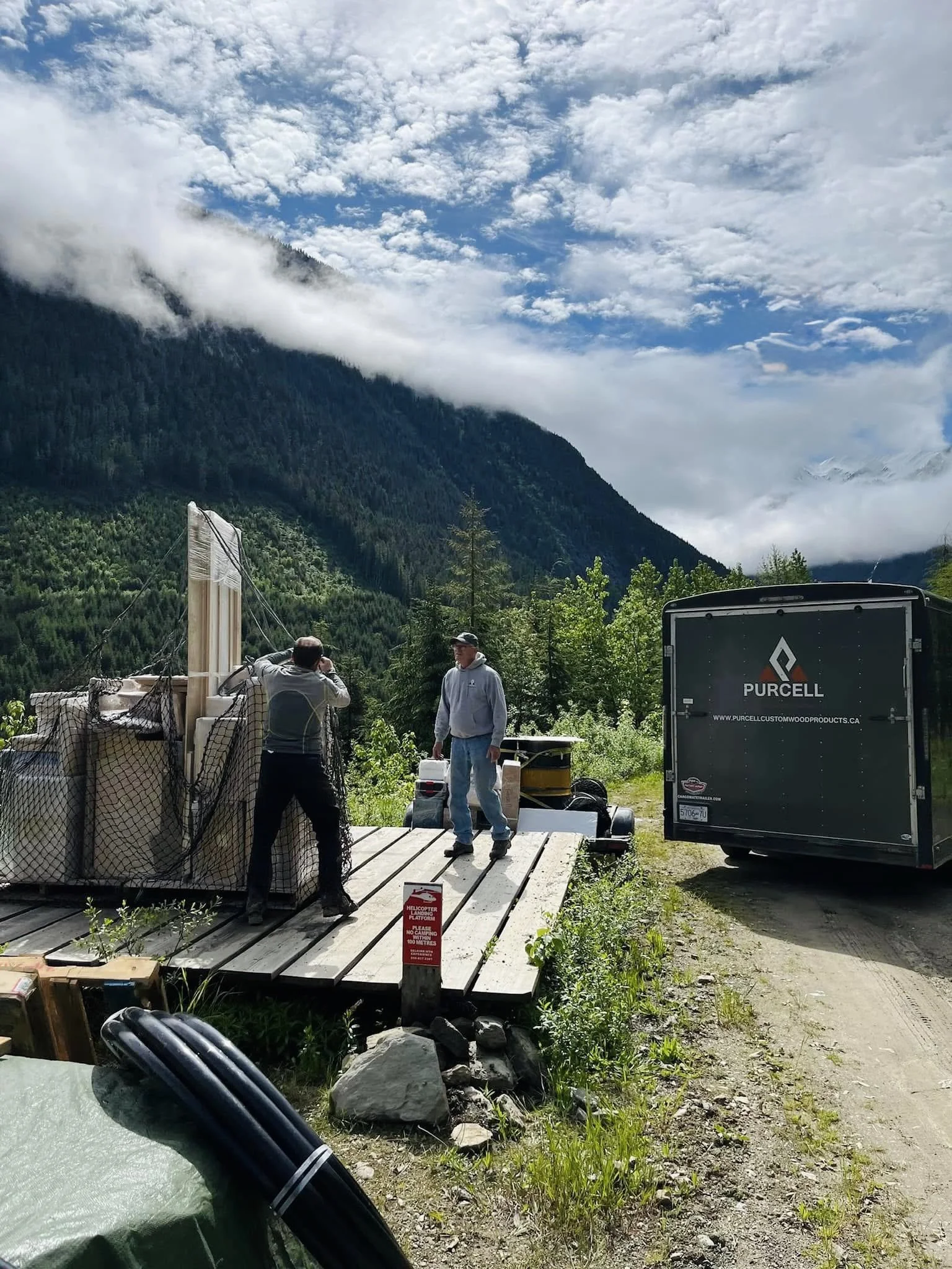 prebuilt cabinets on an outdoor platform, next to a Purcell Custom Wood Products trailer