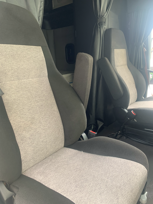 Interior of a vehicle showing gray fabric seats with armrests and seat belts.