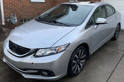 Silver Honda Civic parked on a driveway in front of a brick house.
