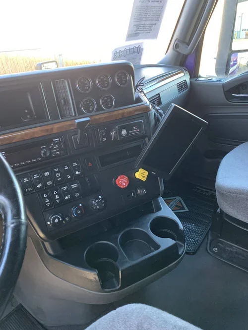 Interior of a truck cab showing dashboard with gauges, a GPS device, cup holders, and other controls