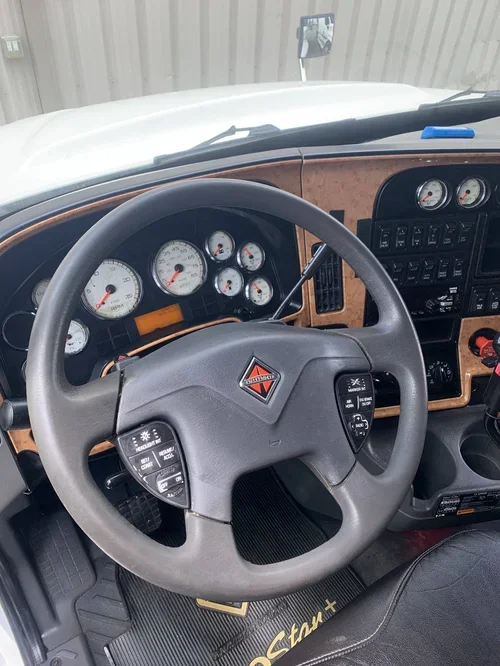 Interior view of a truck dashboard, showing a steering wheel, multiple gauges, and control panels.