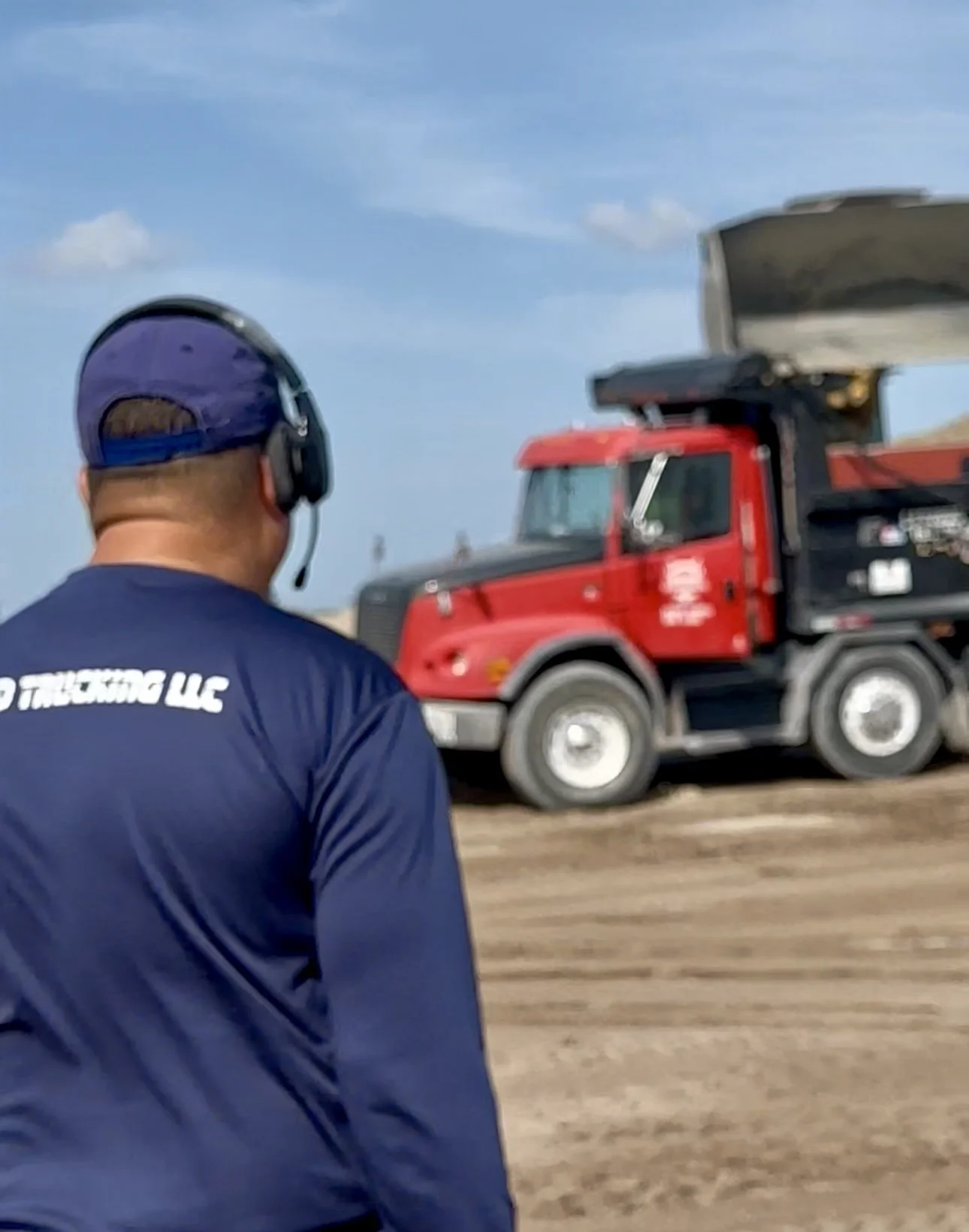 A TRUCK DRIVER WATCHING HIS TRUCK GET LOADED WITH DIRT BEFORE DELIVERY