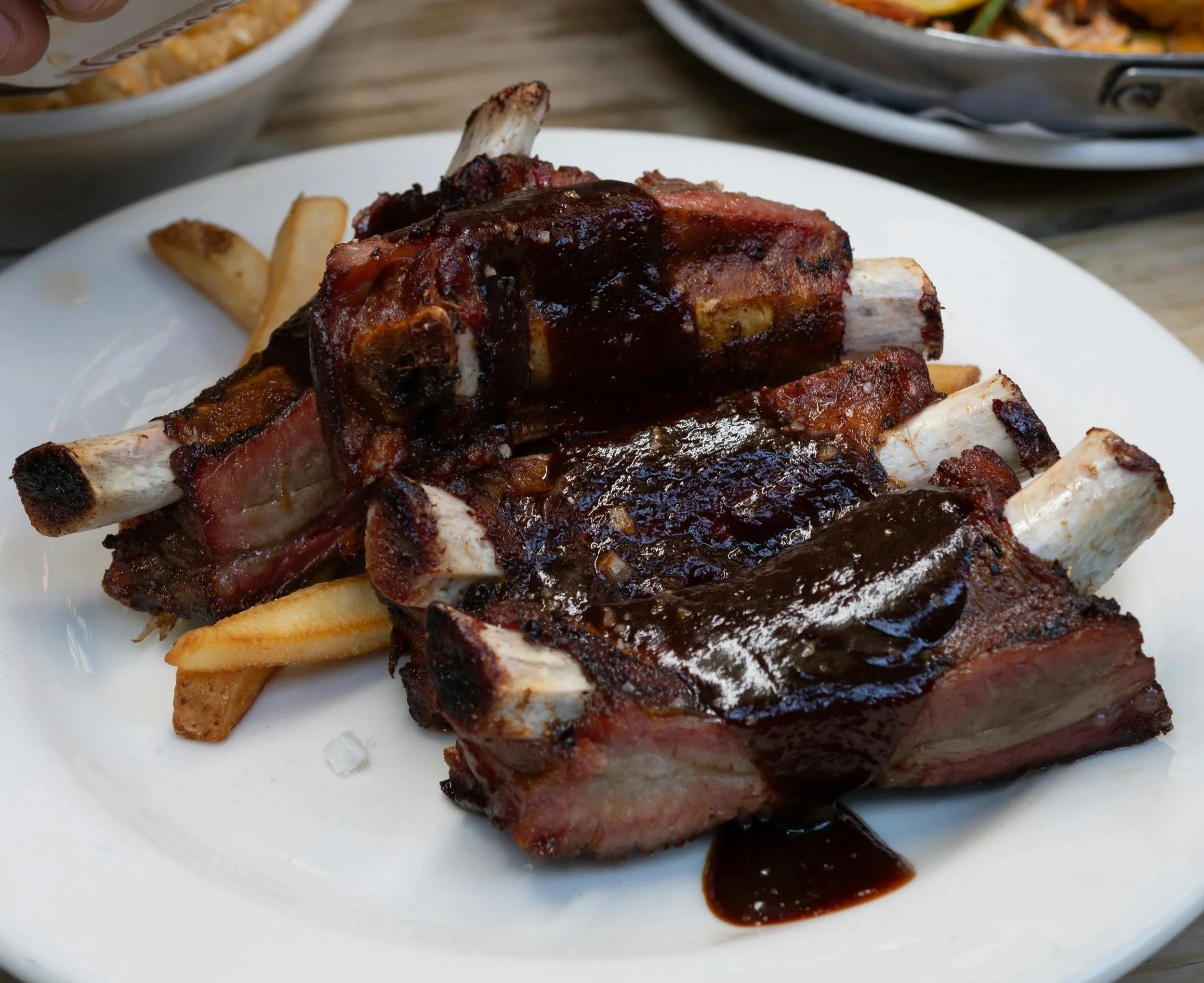 BBQ ribs served with sauce and with French fries on a plate