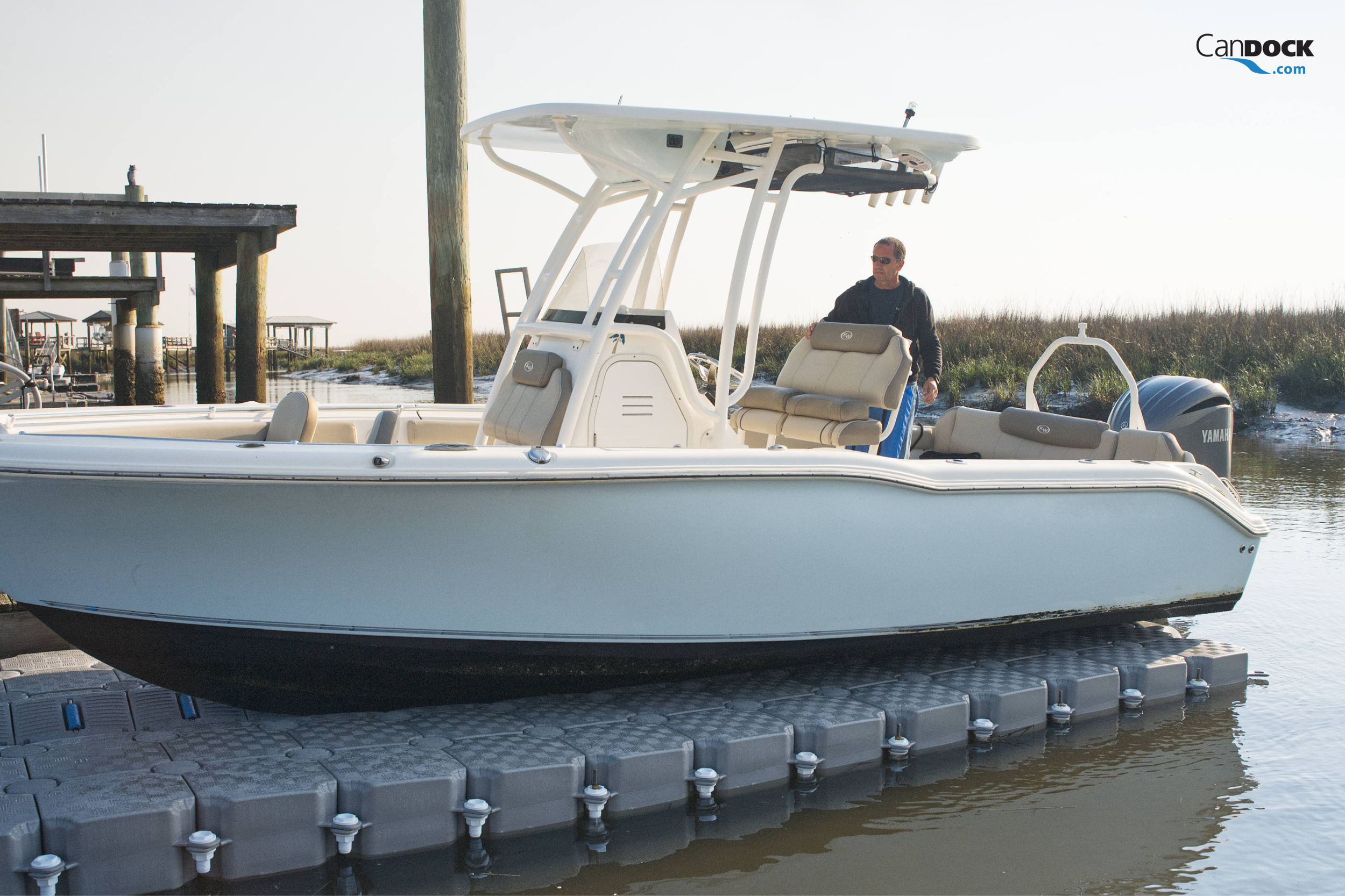 CanDock V-Roll floating boat lift supporting a white center console fishing boat at a residential waterfront dock.