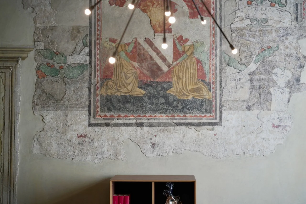 Affresco antico su parete con decori e figure religiose, in parte danneggiato.