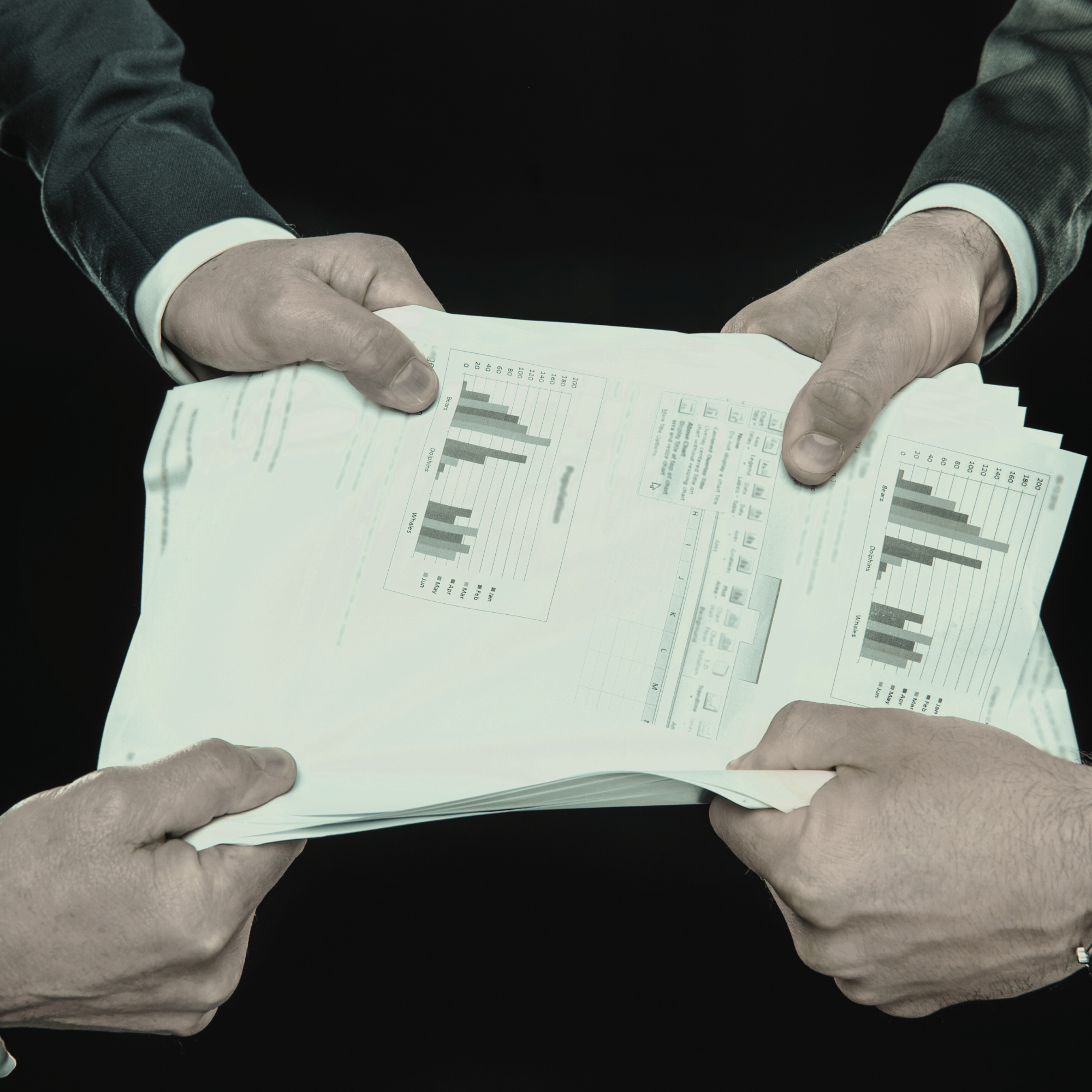 Two people exchanging documents with bar graphs and data spreadsheets.