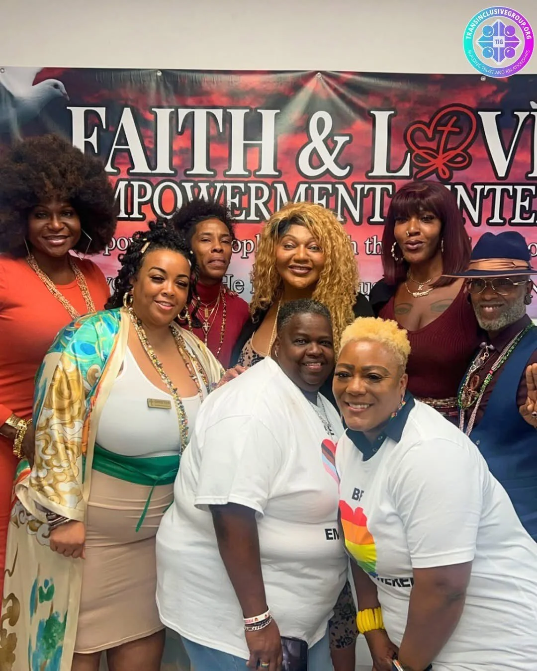 Group of diverse women smiling and posing together at an event with a backdrop that reads 'FAITH & LOVE POWERMENT'.