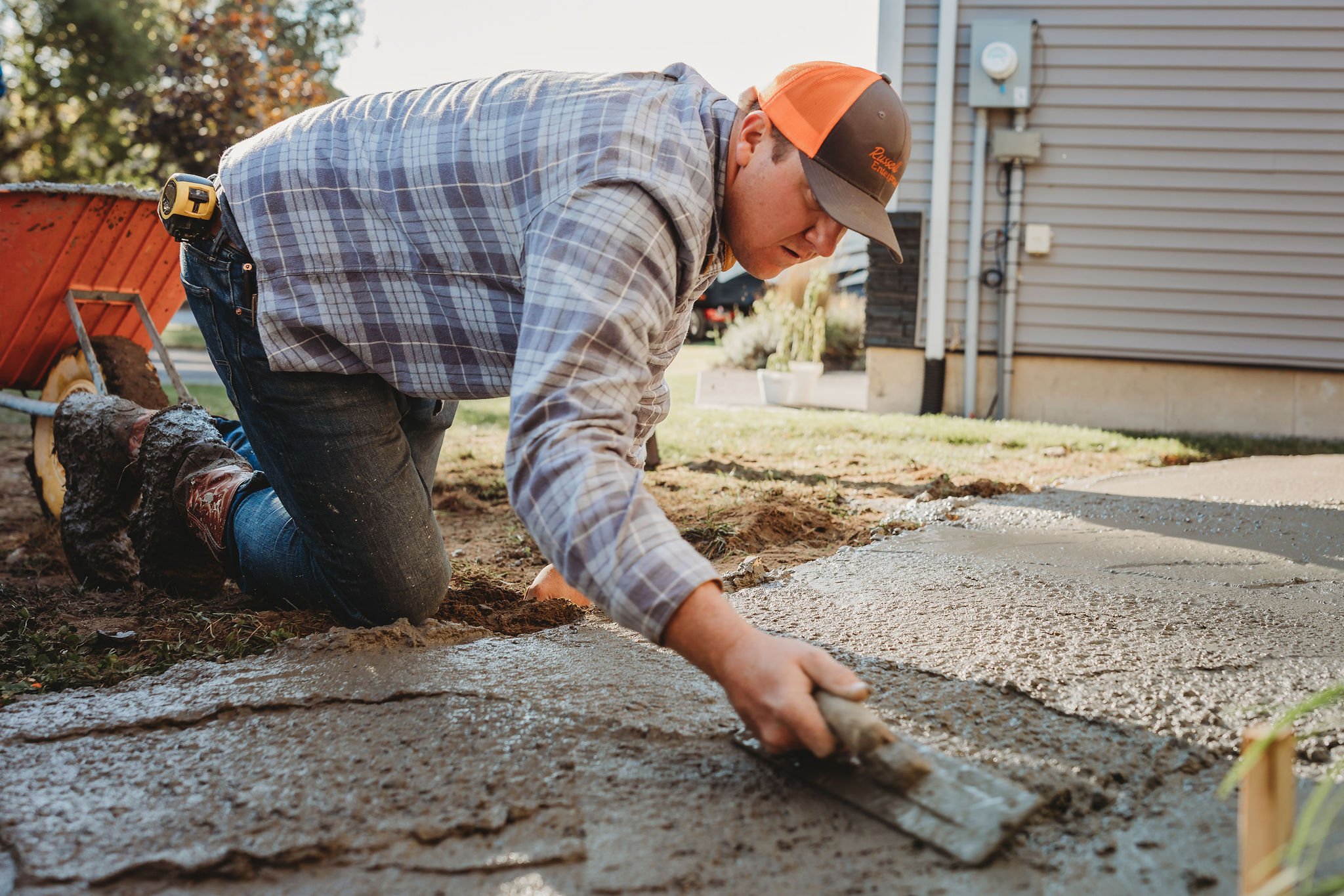 Contractor carefully finishing the surface of a custom concrete walkway for a residential property.