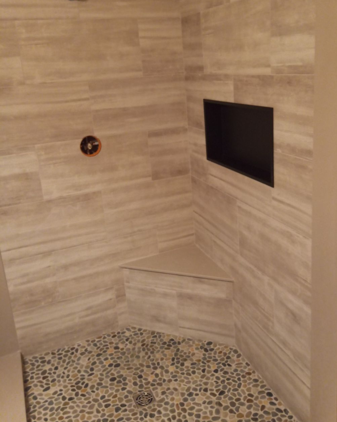 Modern walk-in shower with wood-look tile, built-in bench, and a warm, natural feel.