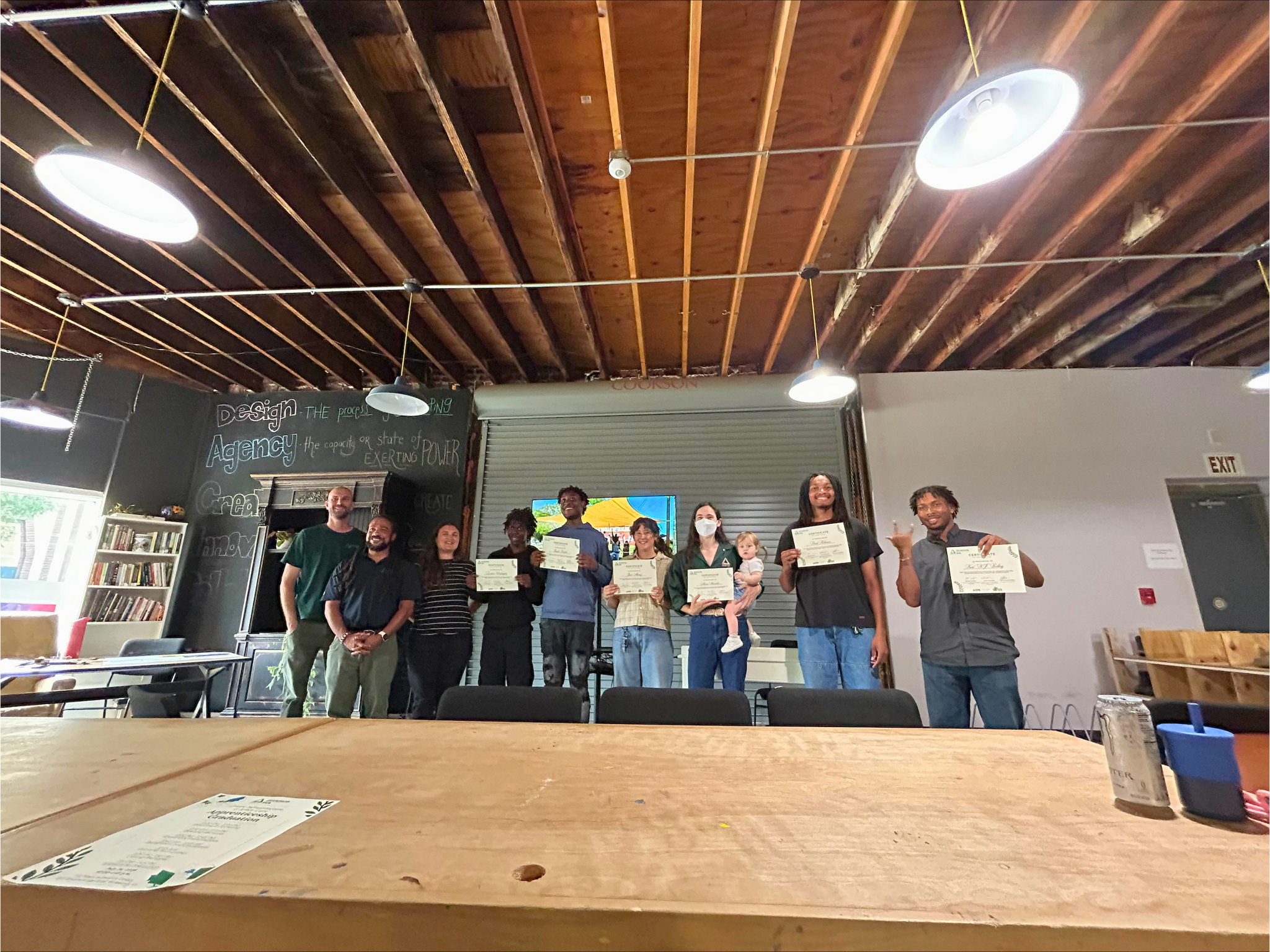 Apprentices from the program’s first cohort pose with their graduation certificates alongside Brian Scott, Nathan Burrell, and Kate Rivara from Groundwork RVA’s staff during the graduation ceremony in August 2026 at Six Points Innovation Center.