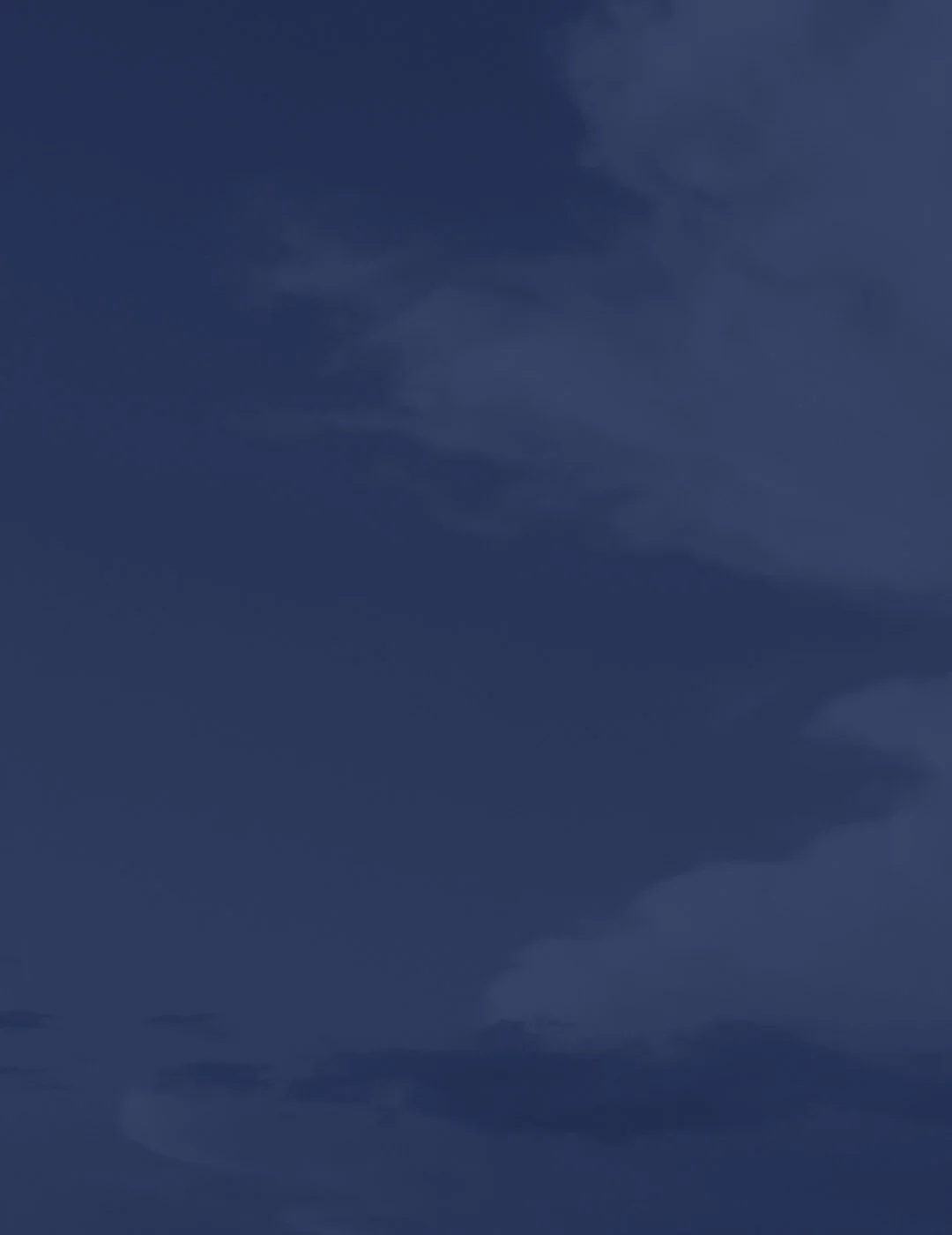 Dark blue sky with scattered clouds during nighttime.
