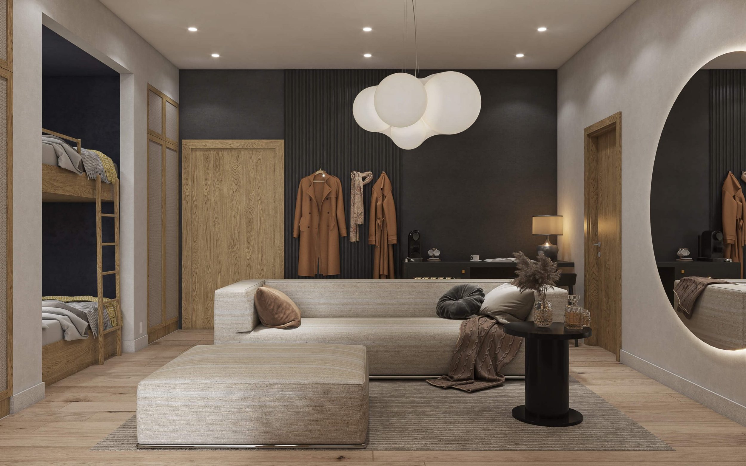 Modern living room with beige sofa and ottoman, black side table with decorative items, large round mirror, black and wood-paneled walls, hanging light fixture, clothes hanging on the wall, and bunk beds on the left side.