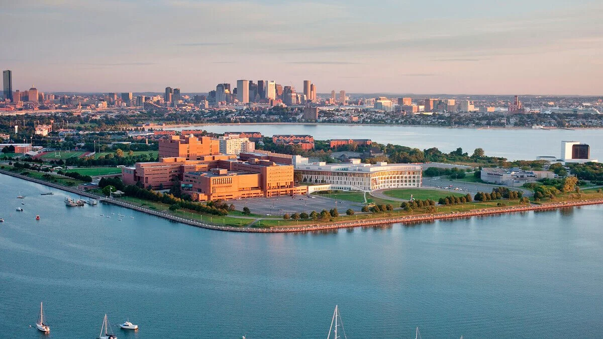 Aerial view of Baltimore Inner Harbor with buildings, water, and sailboats at sunset.