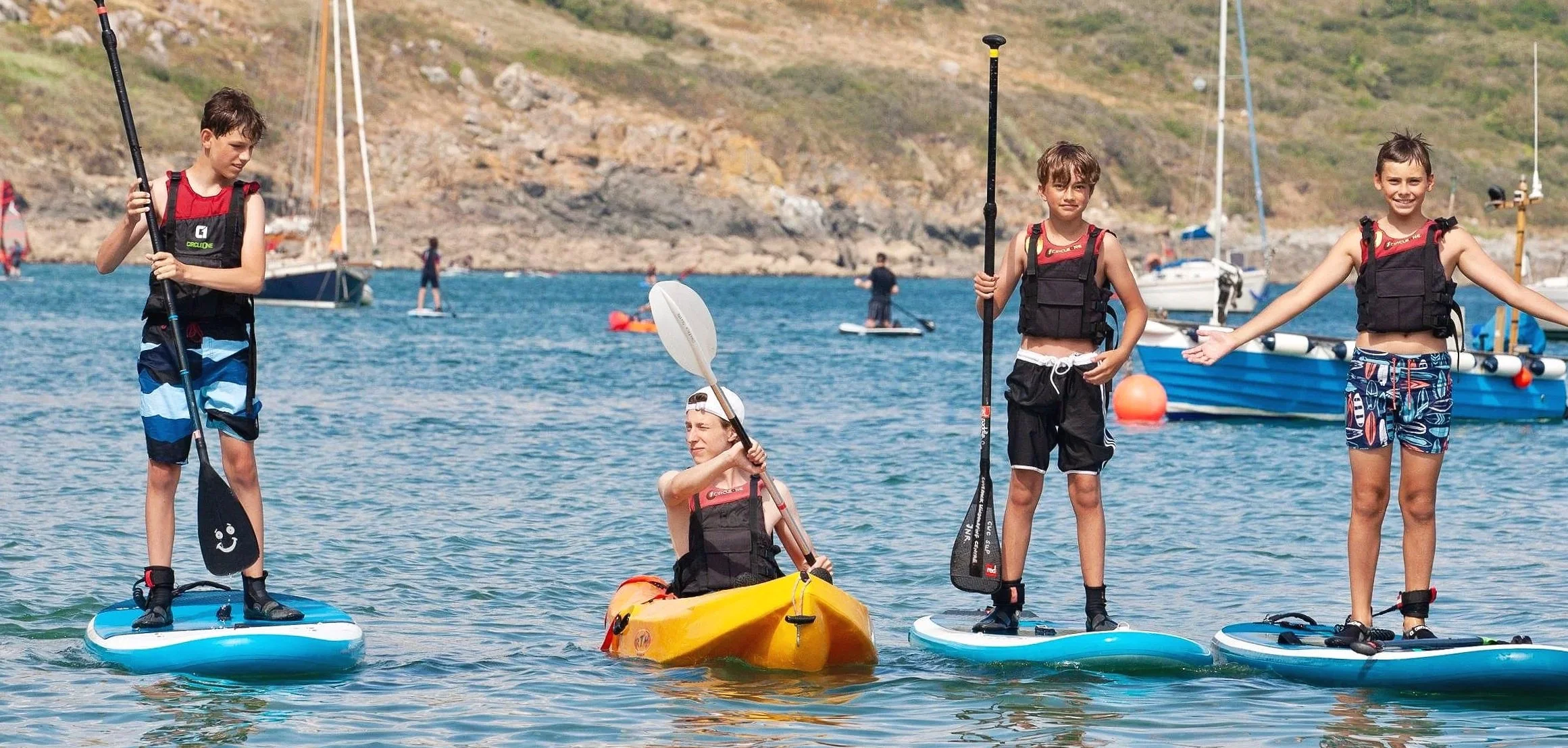 Four children on paddleboards and a kayak