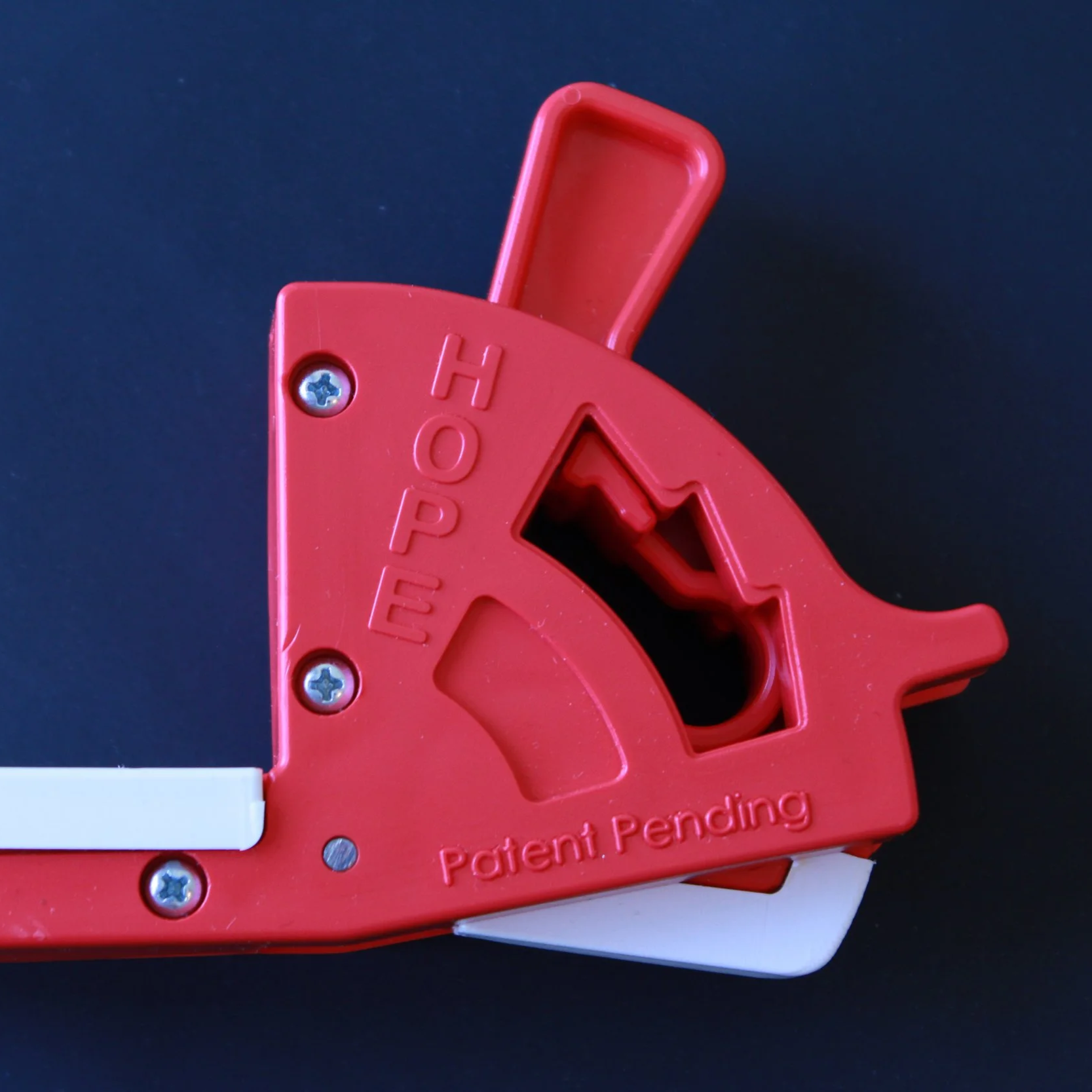 Red device labeled top with a lever and a hole for a screw, with the letters HOPE and the words Patent Pending embossed on it, against a dark background.