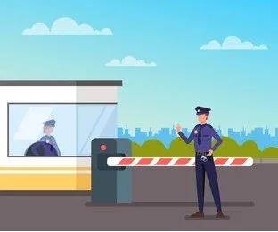 A security guard standing at a checkpoint near a barrier gate, with a security booth in the background and a city skyline in the distance.