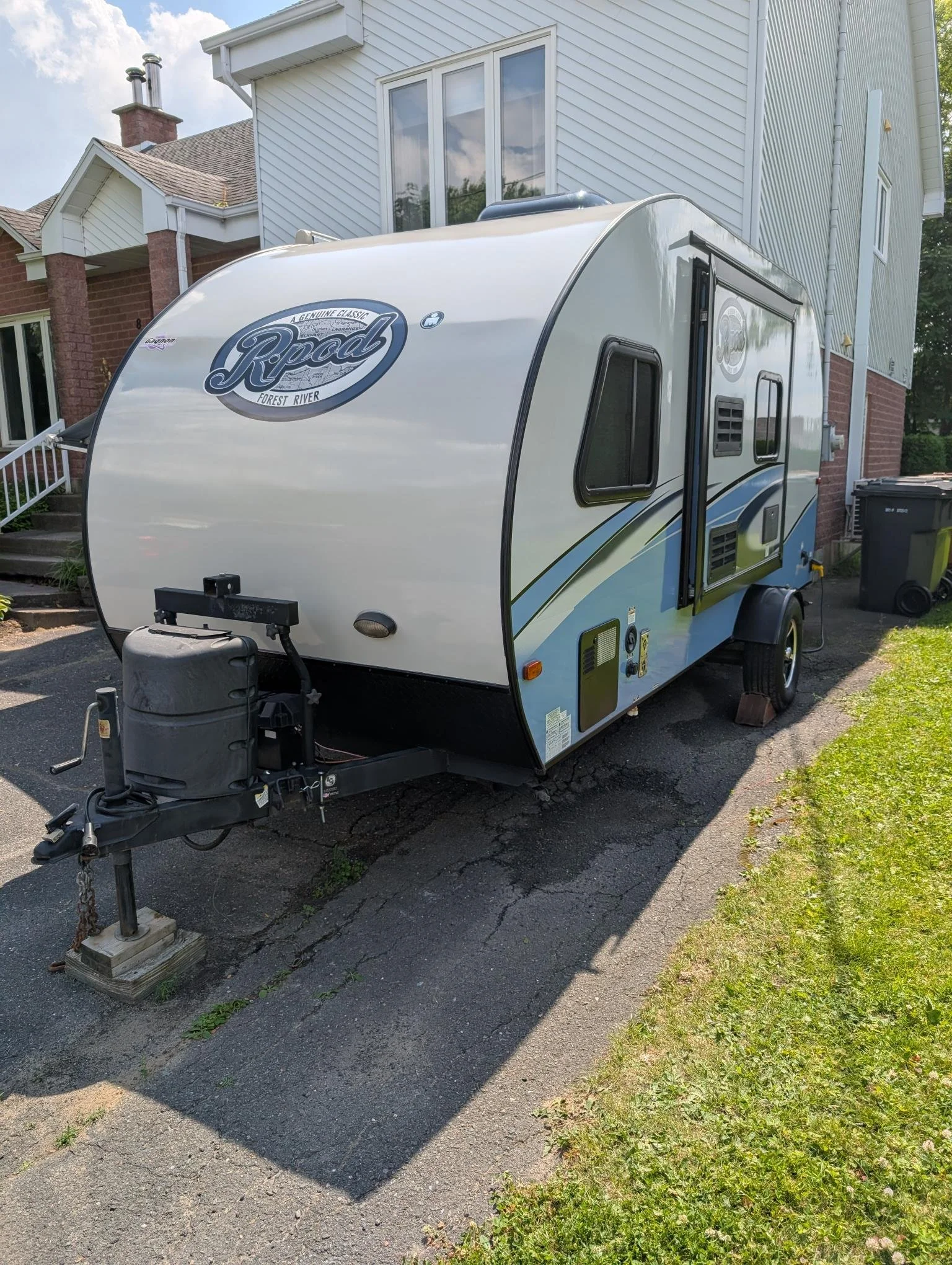 Camping-car stationné sur une allée résidentielle avec une maison en arrière-plan.