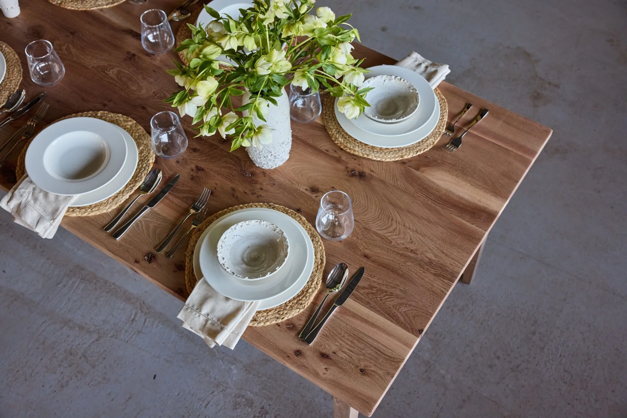 A dining table laid with neutral crockery. With sustainably sourced British elm timber
