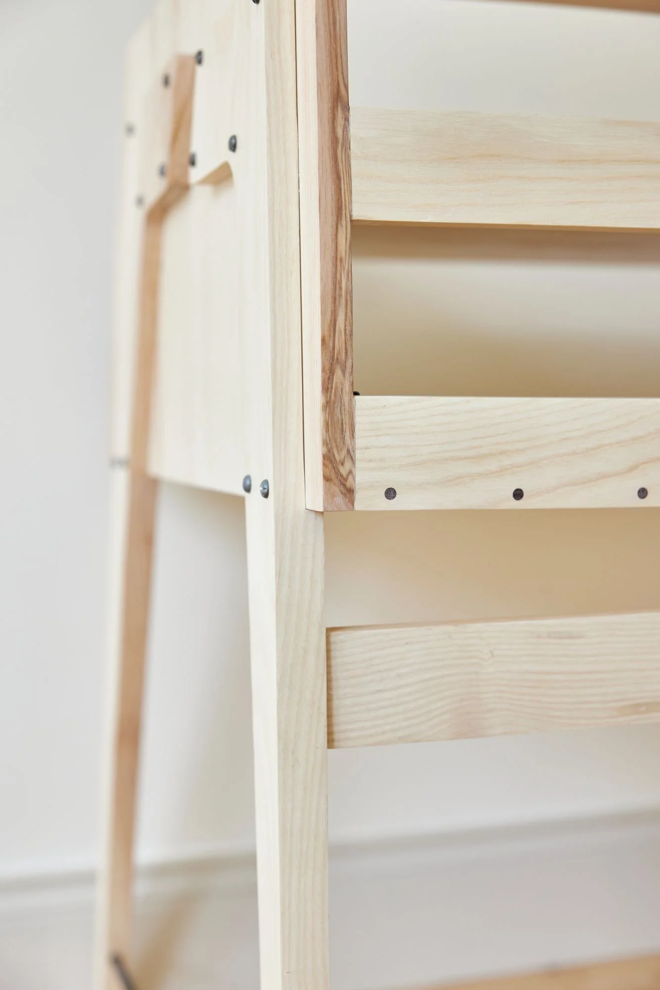 Detail of a bespoke music production desk where the cables can fall easily over the back of all 3 shelves
