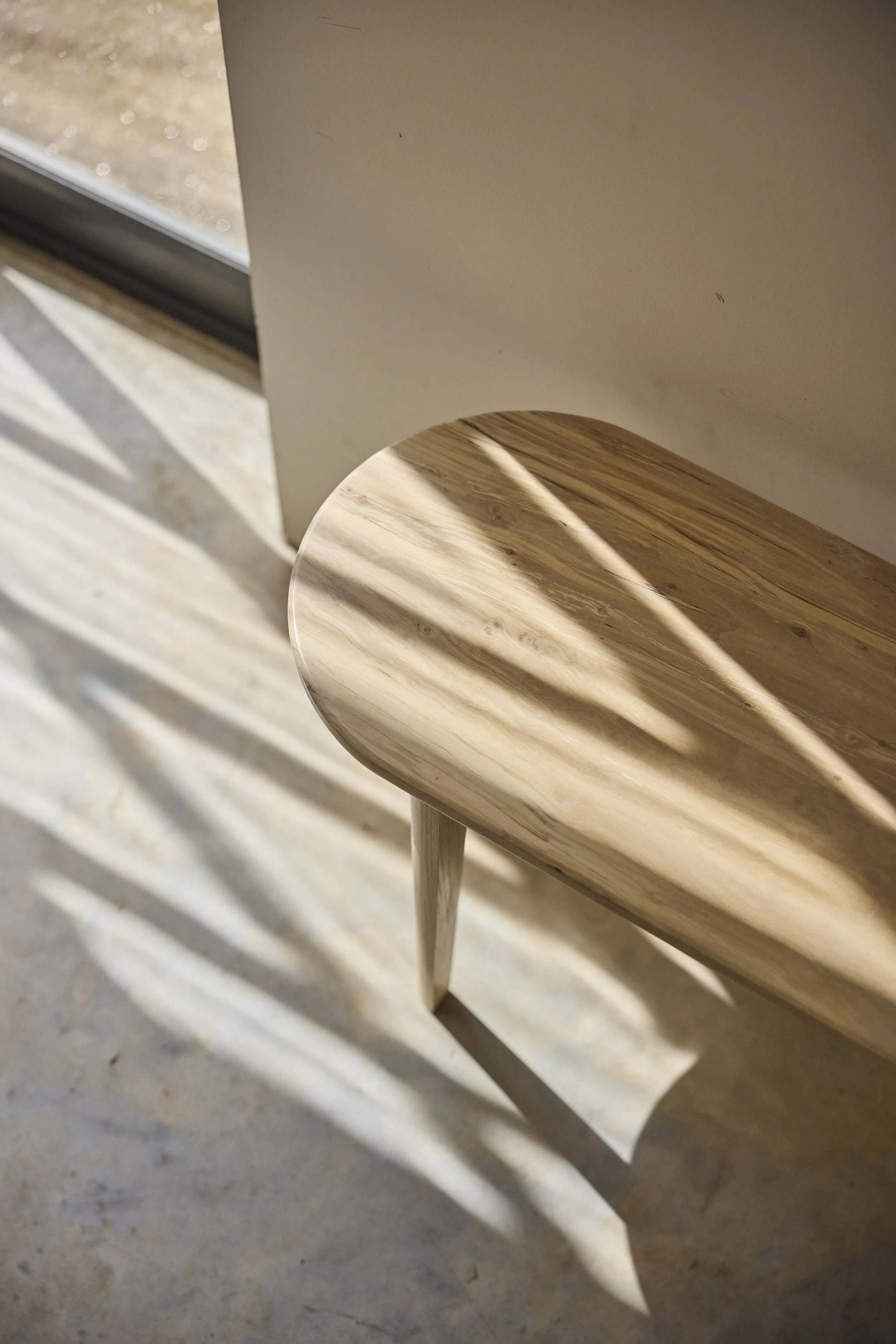 A close up of a spalted silver birch bench handmade in Bristol with abstract evening light and shadows in a minimal context