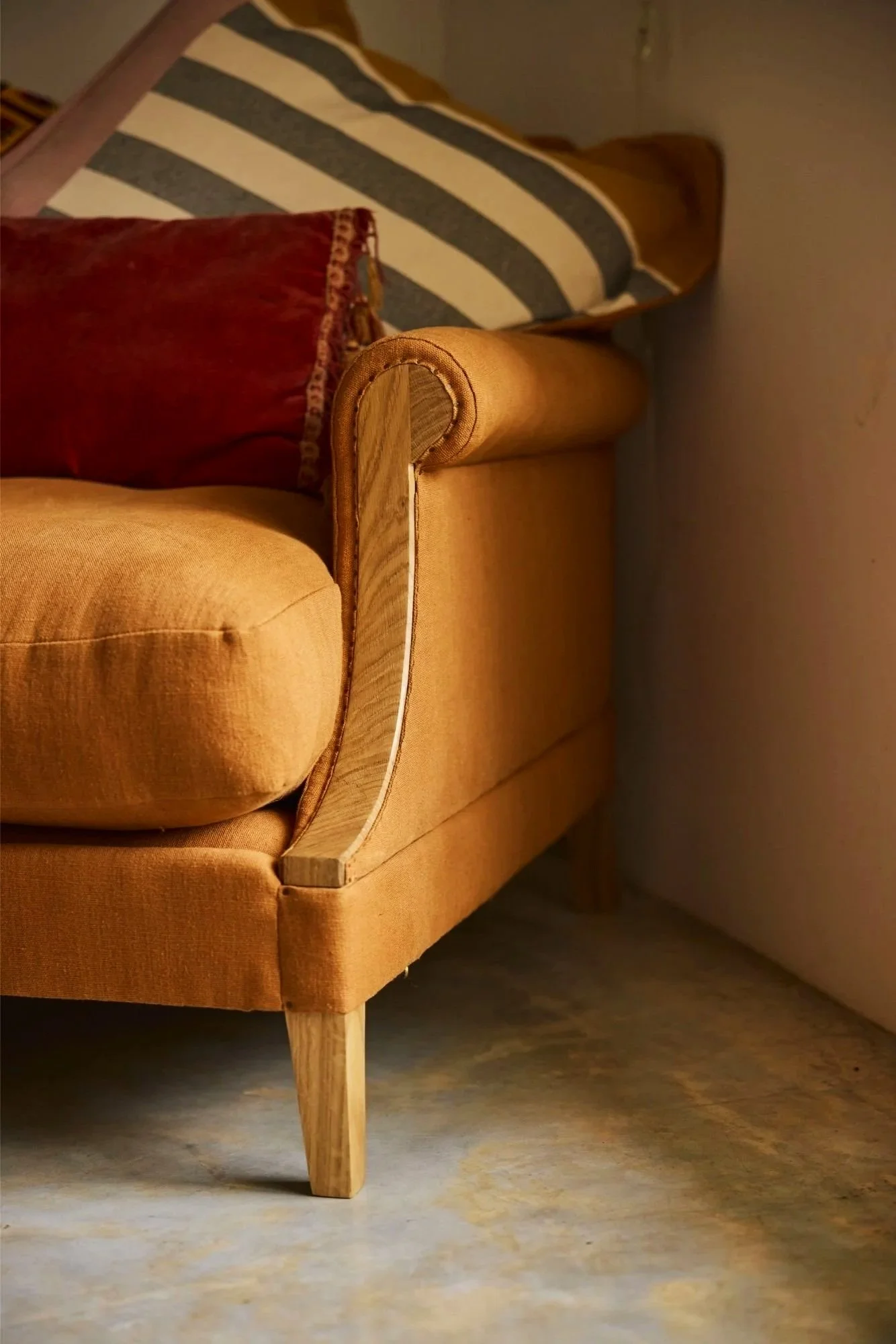 Detail of The Aldan Loveseat by Trew & Bold upholstered in 'brick' linen by designers guild contrasting the soolid oak frame