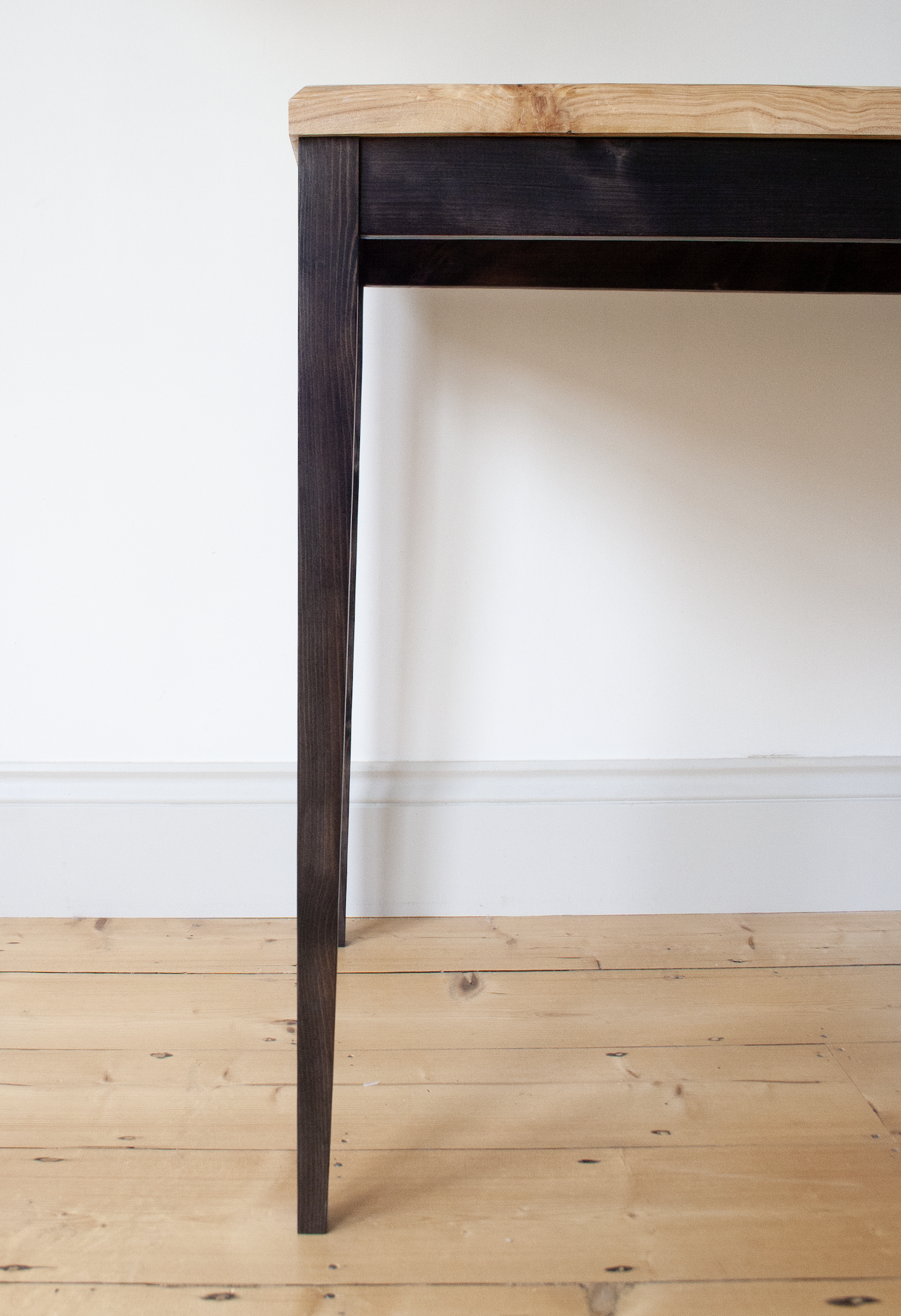Close-up of the elegant charcoal stained legs of the Calder Table