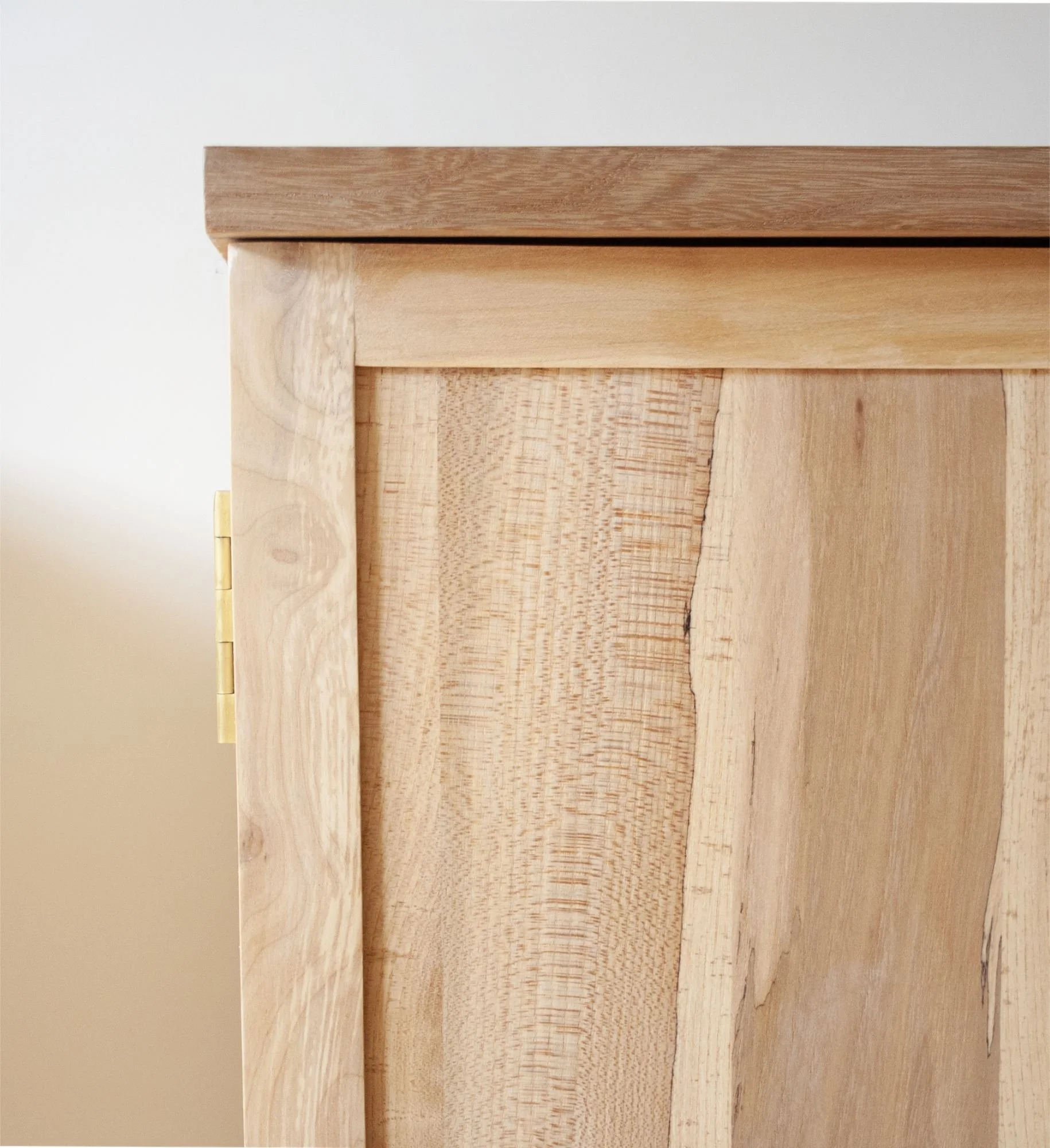 Close-up of a handmade cabinet, showing different types of light and dark wood with visible grain patterns.