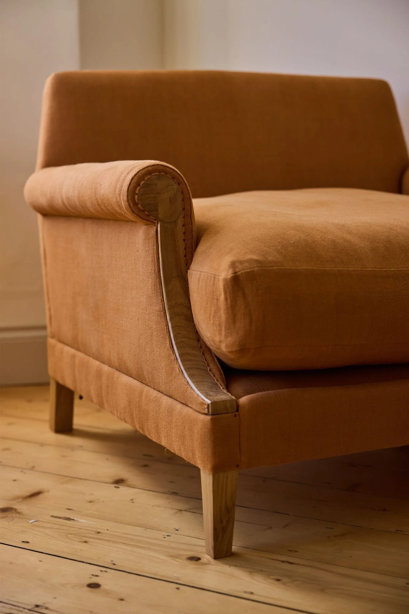 An oak armchair upholstered in an orange linen made to order with adjustable dimensions