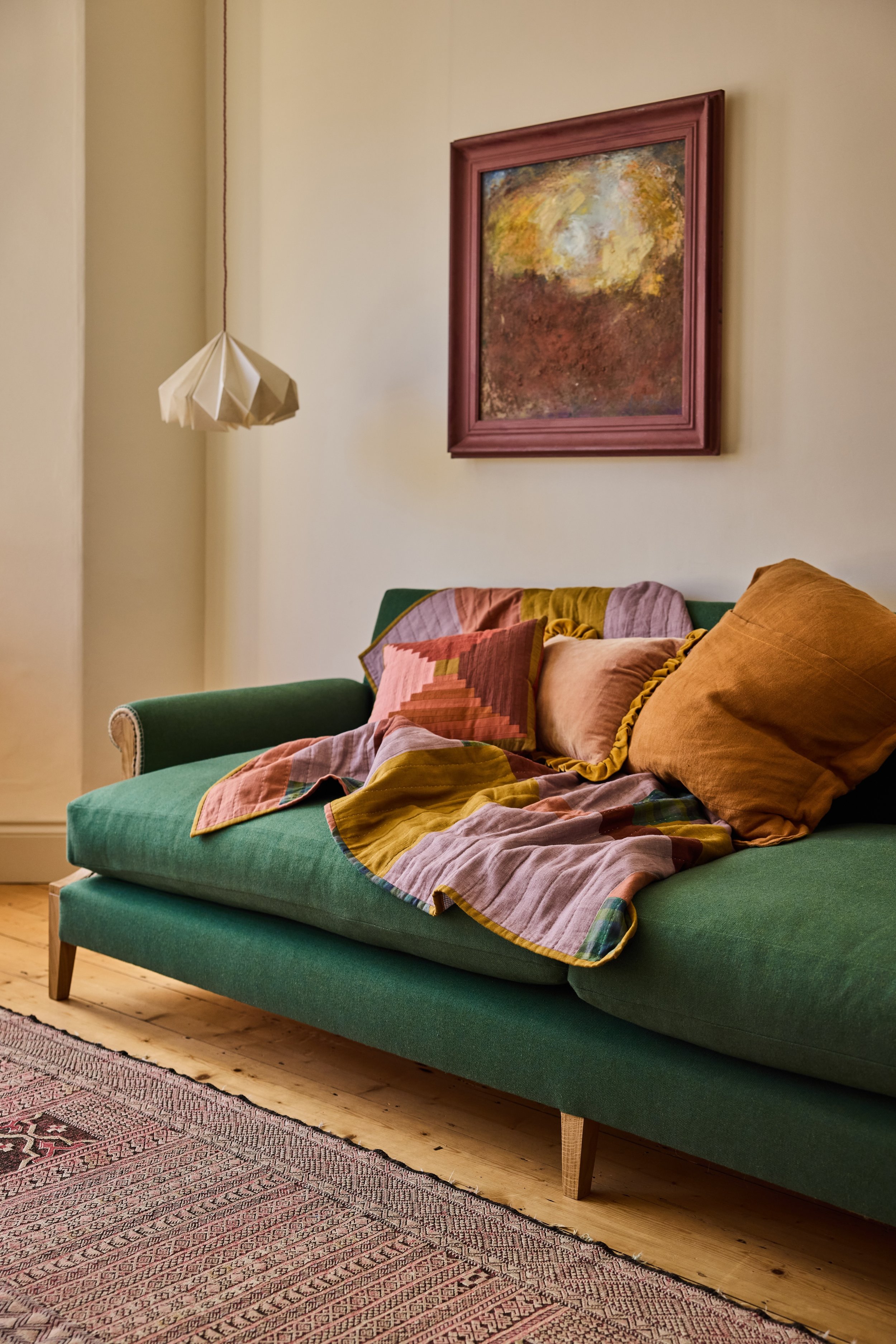 A large bespoke solid oak sofa shown in a green wool fabric traditionally made and uphostered but expert craftspeople in Bristol.