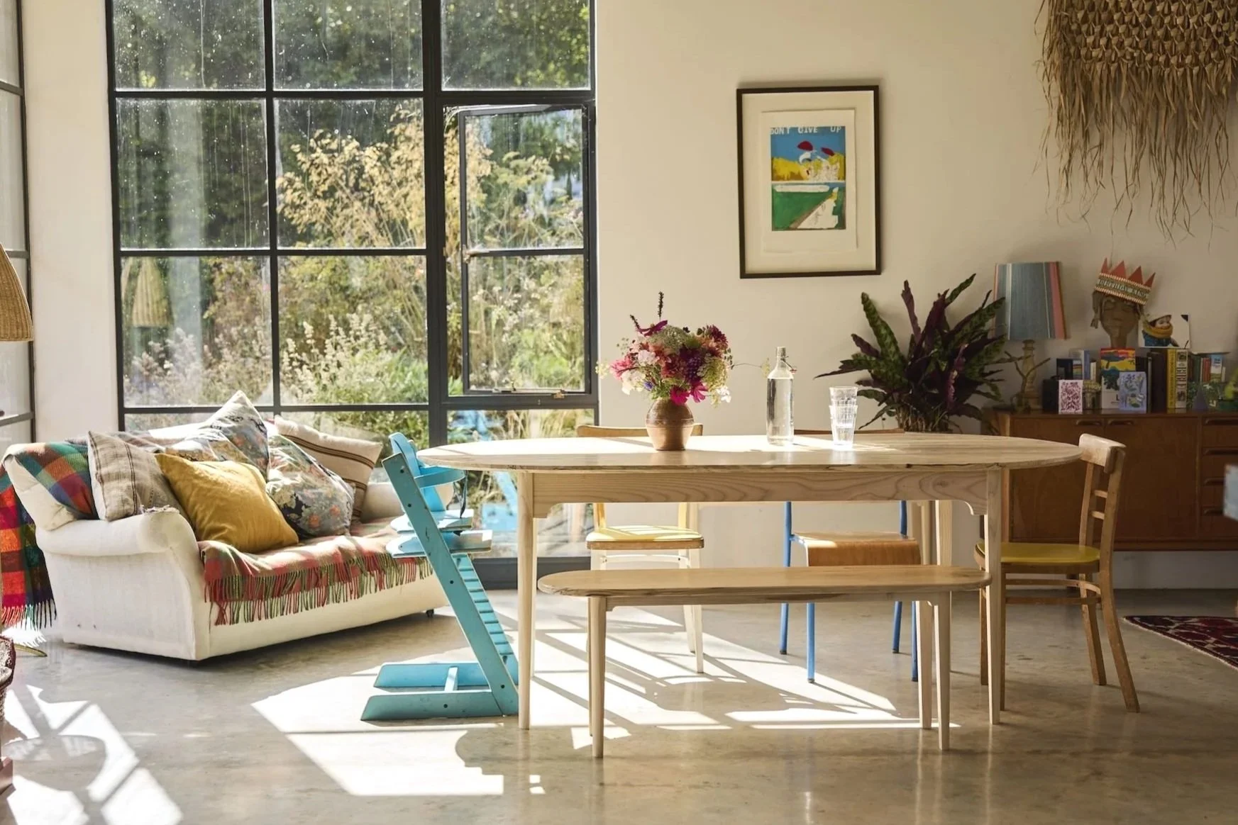 A dining table set made from solid ash and silver birch in a family home with big bright windows and a colourful vase of flowers on the table