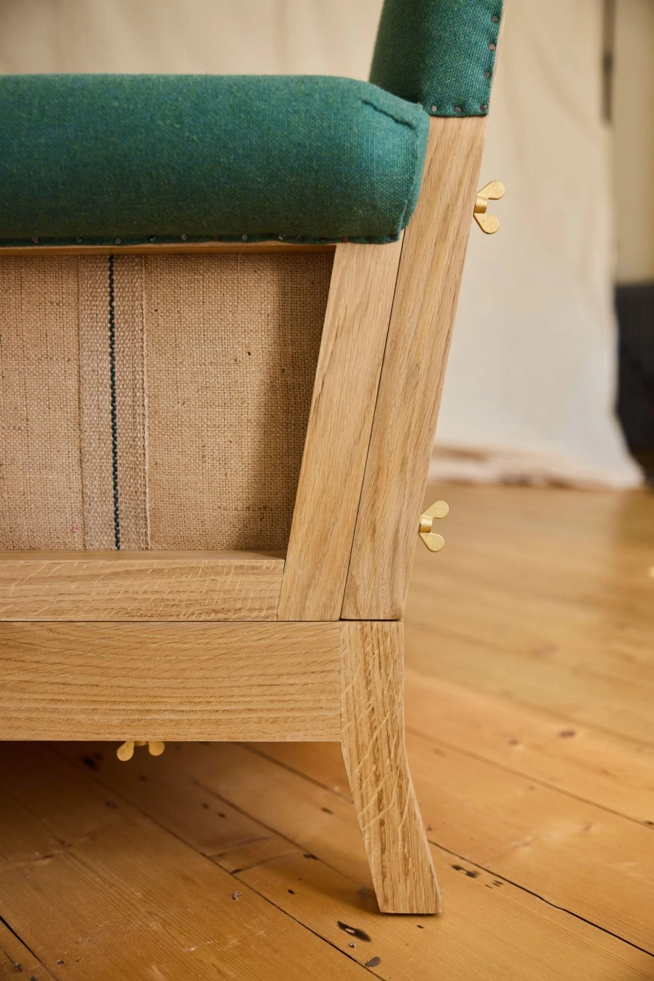 Detail of a dismantleable bespoke sofa made with solid oak exposed hessian and green wool fabric