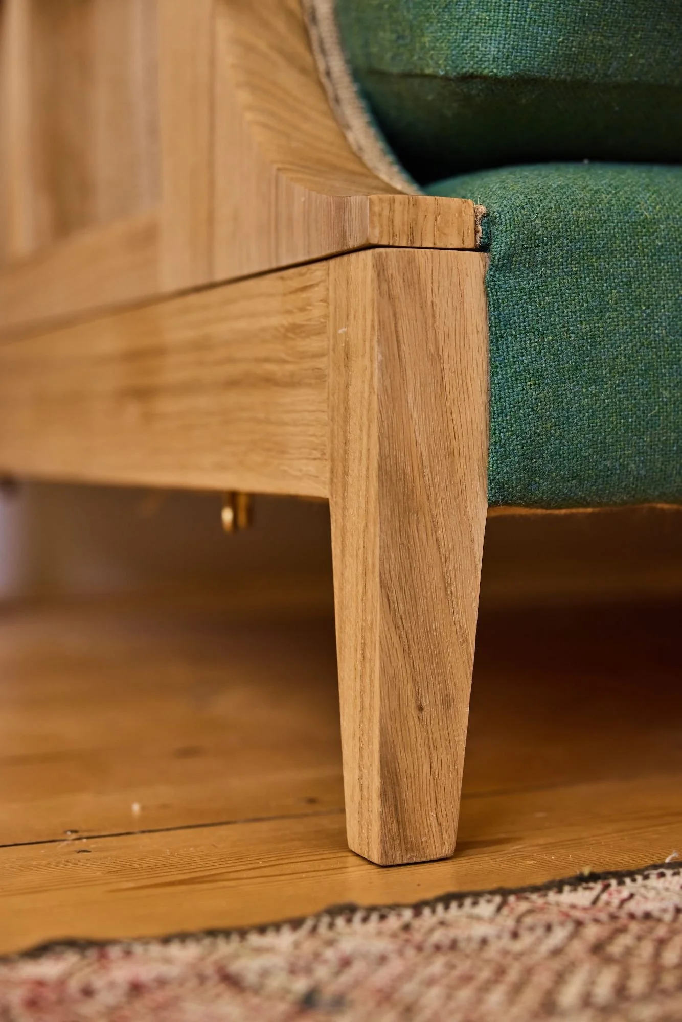 Tapered leg detailing of the frame on a custom oak sofa made in a furniture workshop near the Cotswolds
