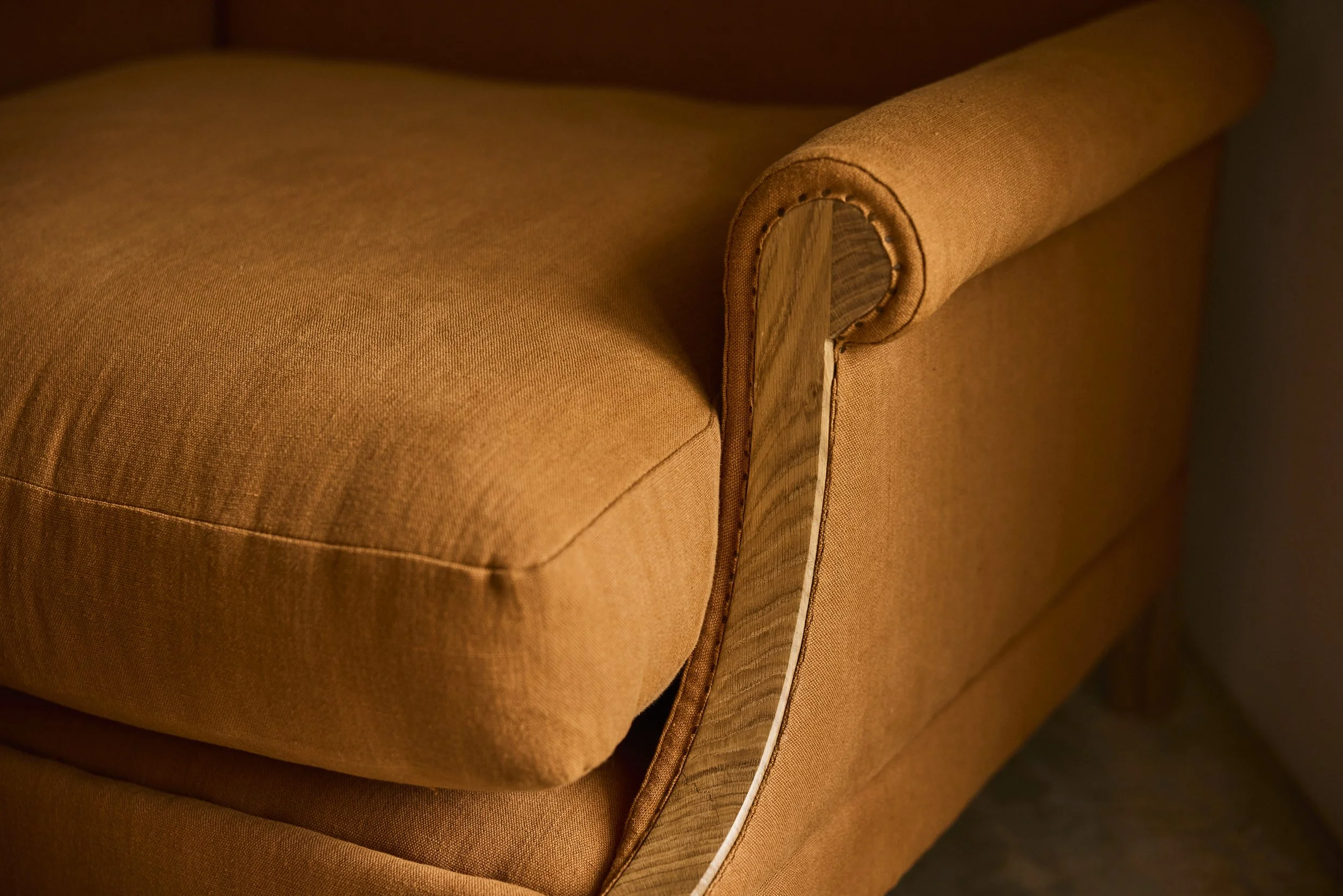 An orange armchair with a solid oak frame and traditional upholstery made in Bristol
