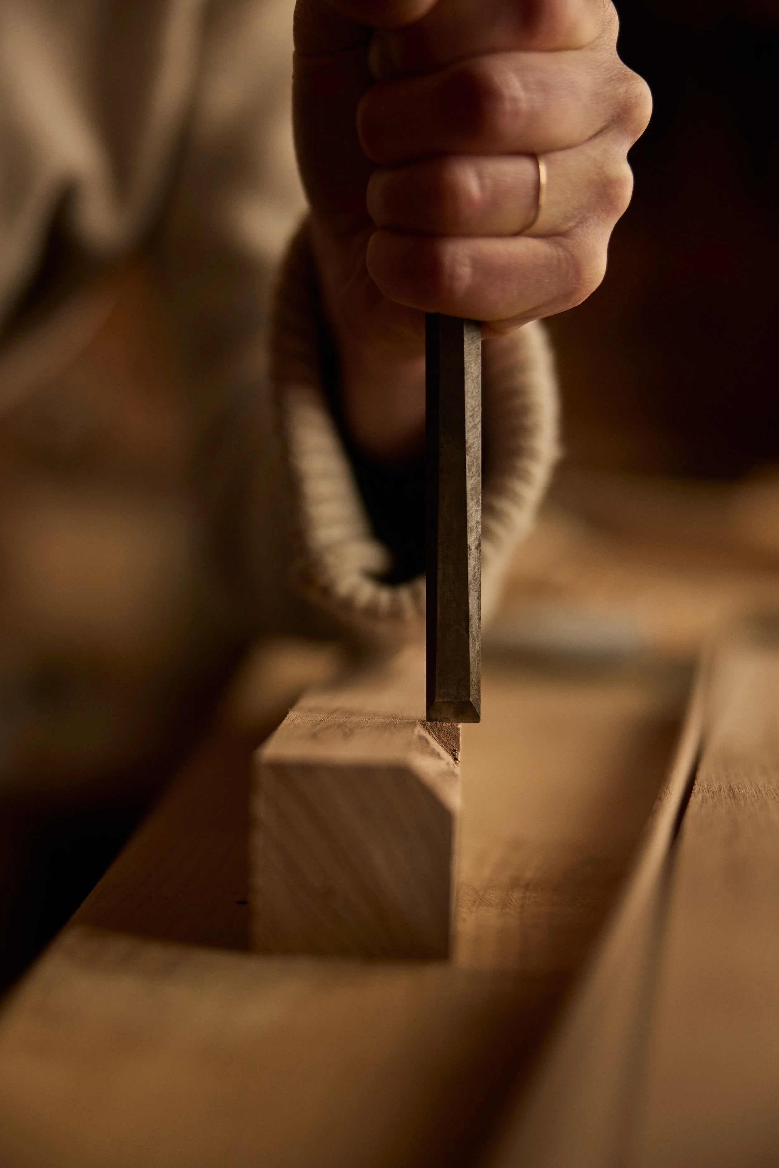 A female woodworkers hand carefully hand chisels a stopped chamfer in a workshop near Bath