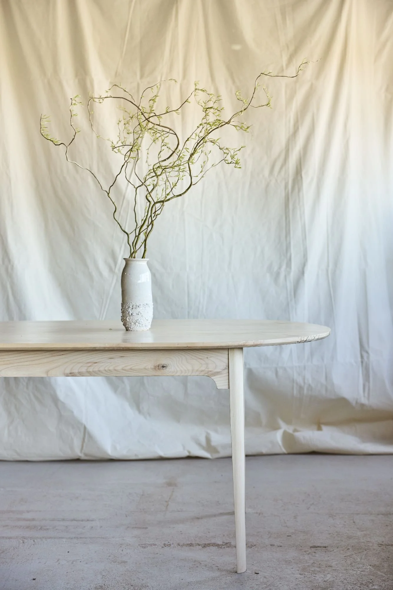 A minimal shot of a bespoke ash and silver birch dining table with a hand made vase on the table