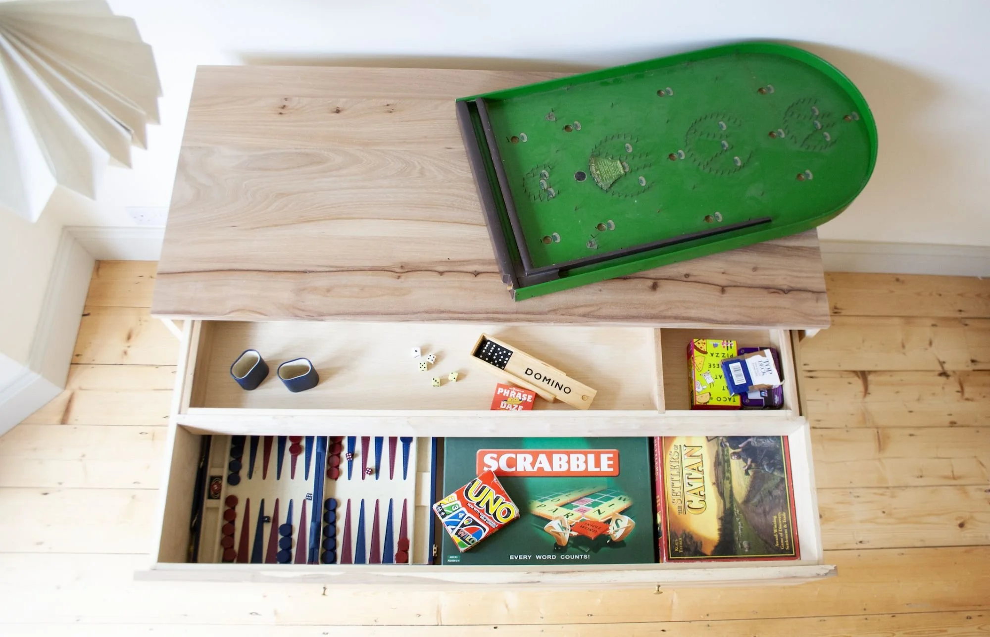 A wooden drawer filled with various board games and game pieces, The `Farrow Chest of Drawers made from solid british elm