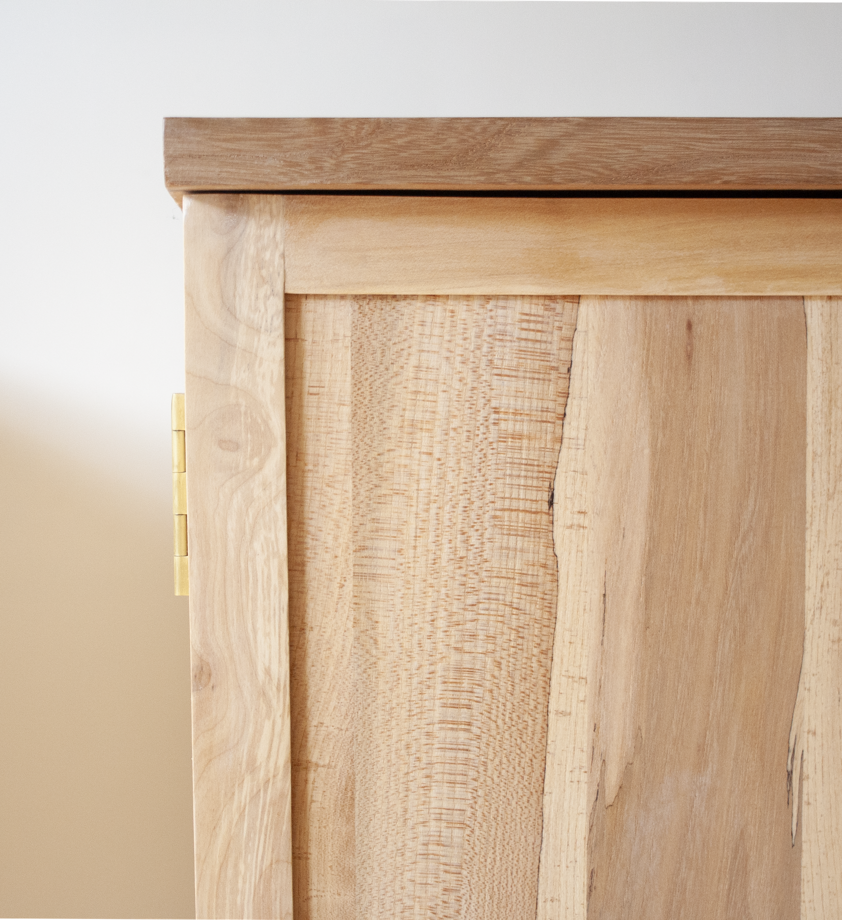 Close-up of the corner of a wooden cabinet or piece of furniture, showing the natural wood grain and joinery.