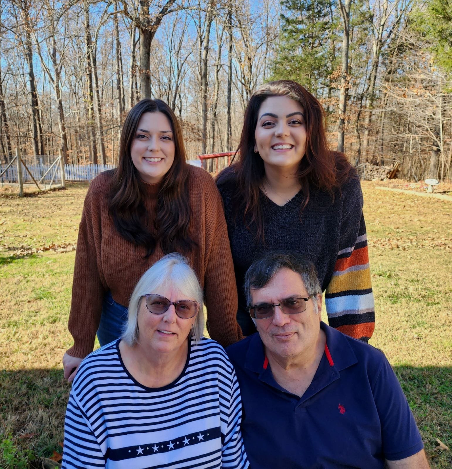 Women smiling with her sister, mom, and dad posing for a group photo