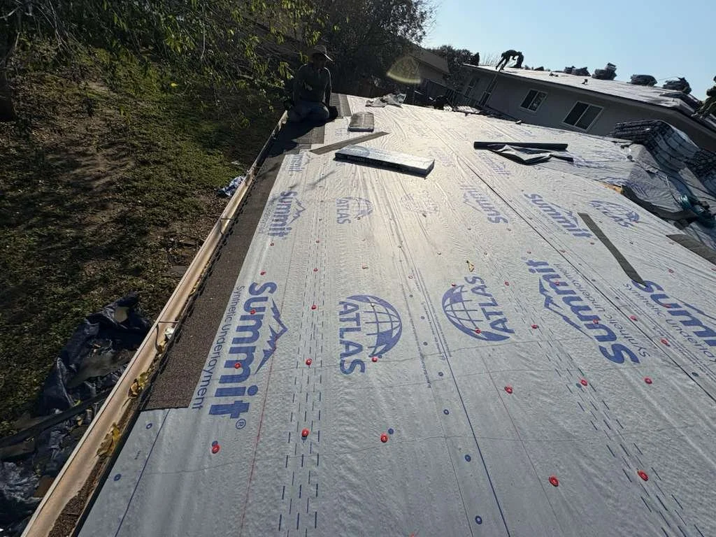 Construction worker installing a new roof on a building, with insulation and roofing materials visible.