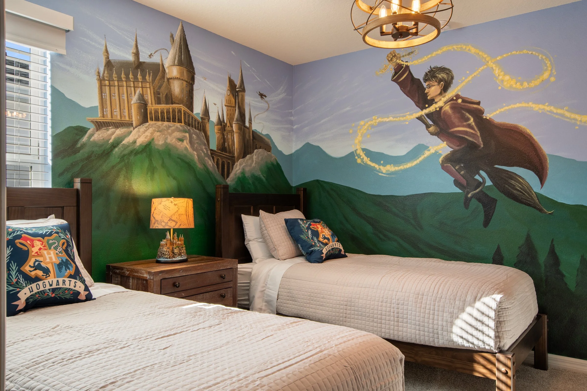 Children's bedroom with Harry Potter themed mural depicting Hogwarts castle on a mountain and a wizard flying on a broomstick casting a spell.