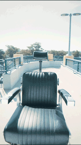 Empty black leather seat on a ferry deck with city skyline, trees, and streetlights in the background.