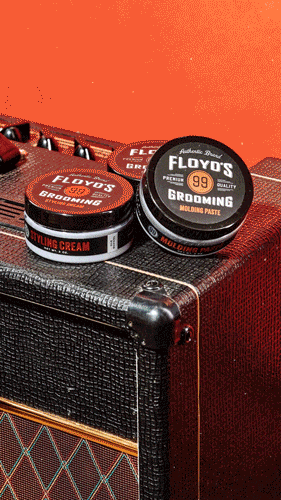 Two tins of Floyd's of Head Grooming Molding Paste on a guitar amplifier, with a red guitar in the background.
