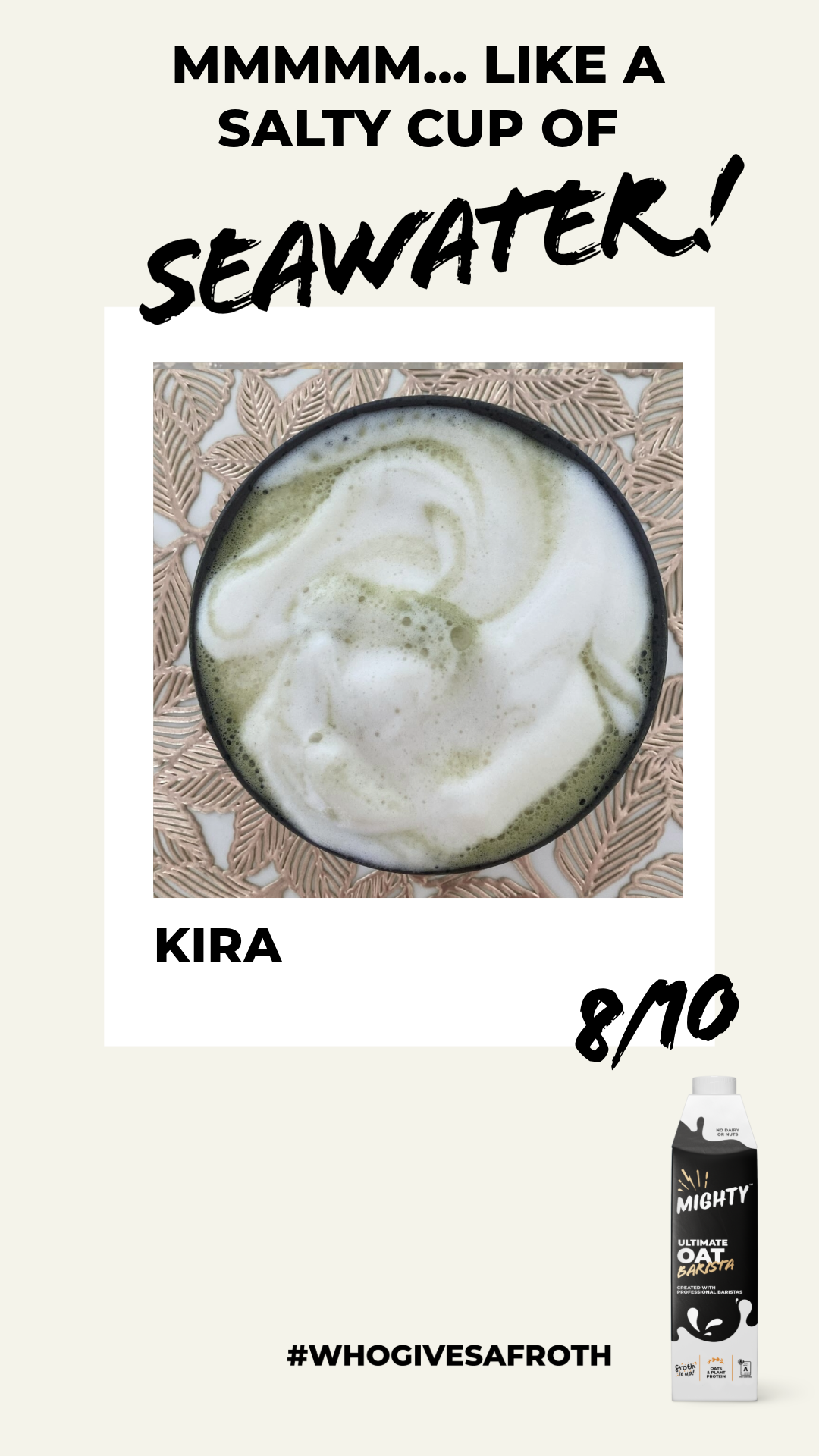 A frothy drink in a black cup with foam art on top, placed on a decorative woven mat.