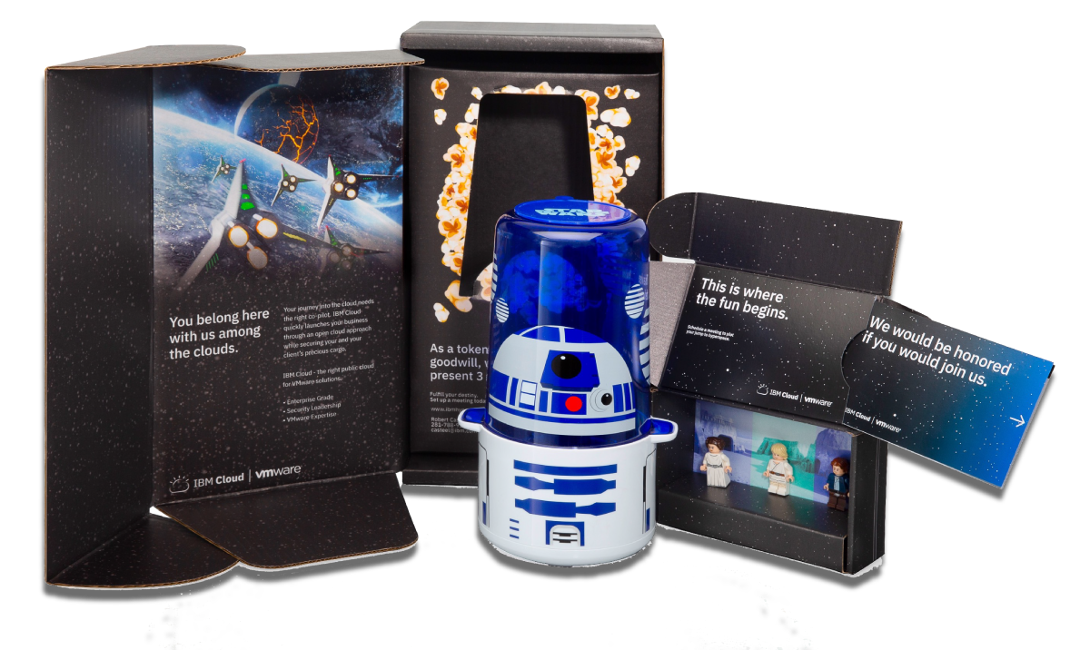 Star Wars R2-D2 themed popcorn container with merchandise and promotional materials from IBM Cloud and VMware.